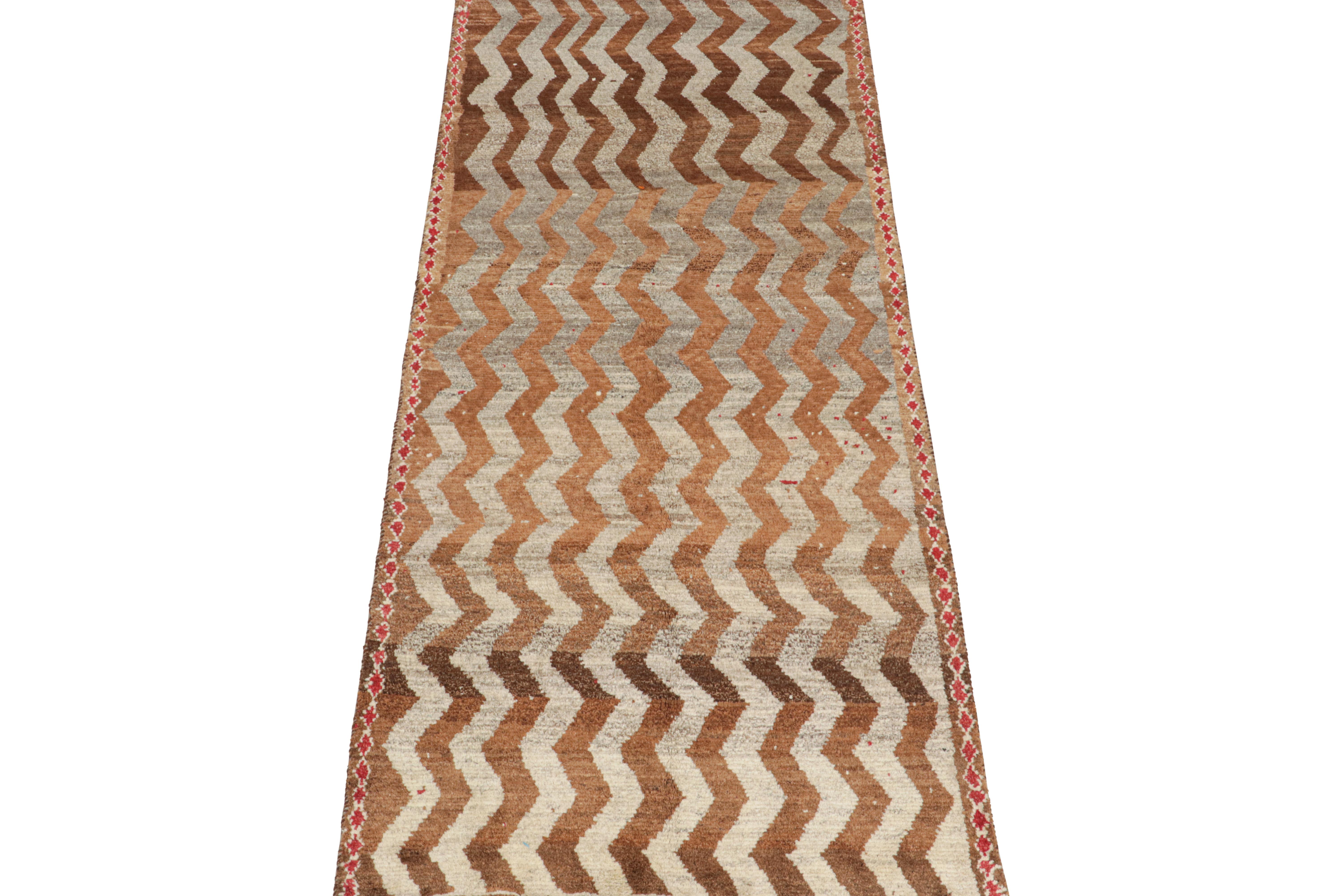 This vintage 4x9 Persian rug is a mid-century tribal piece, hand-knotted in wool circa 1950-1960.

Its design enjoys chevron patterns in rich brown, beige, and gray tones within a border of red diamonds. Connoisseurs will admire this rich piece of