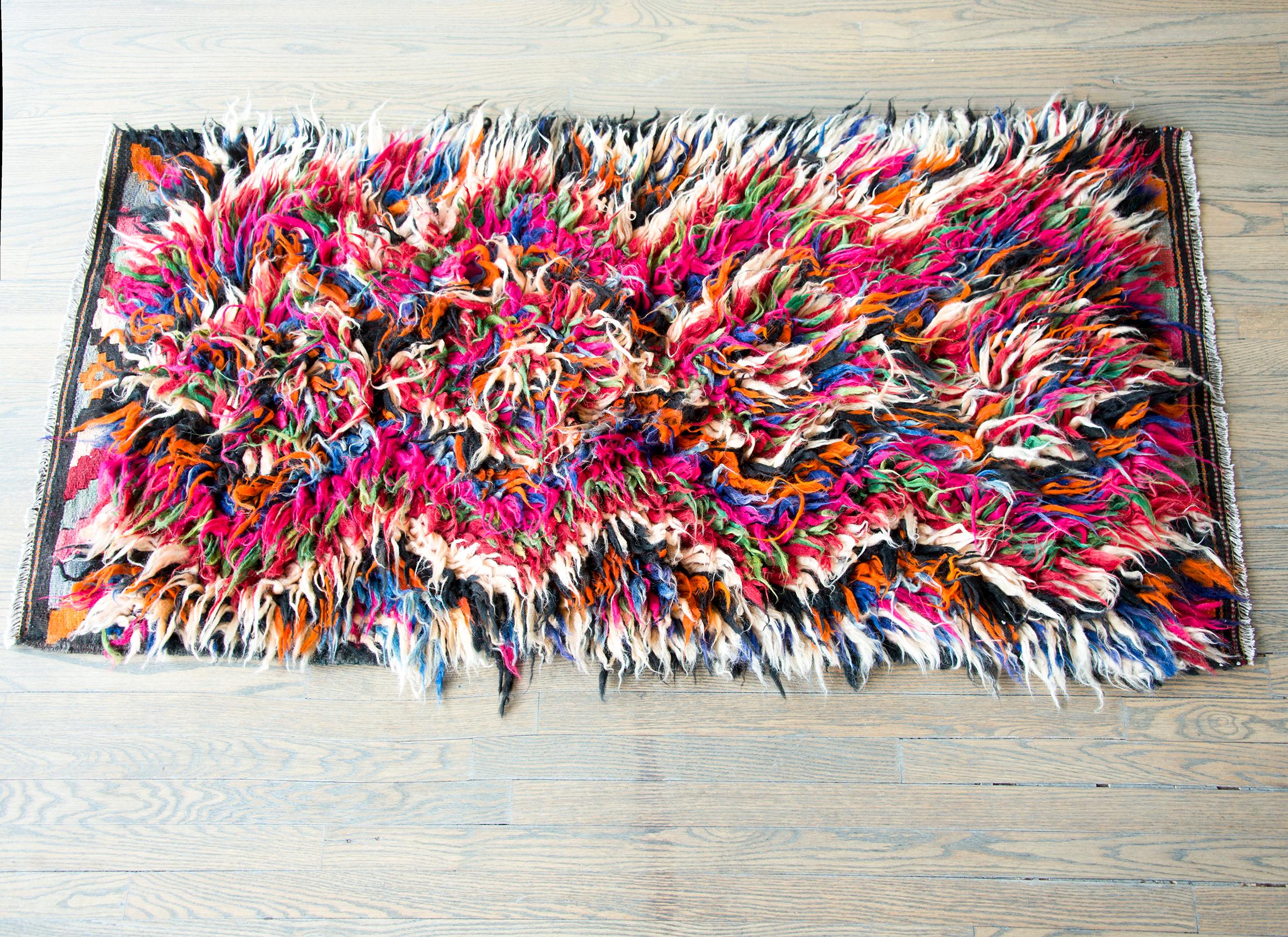 A striking mid-20th century Persian tulu rug with a fabulous shaggy wool diamond pattern woven in brilliant pinks, indigos, greens, oranges, and white wool.