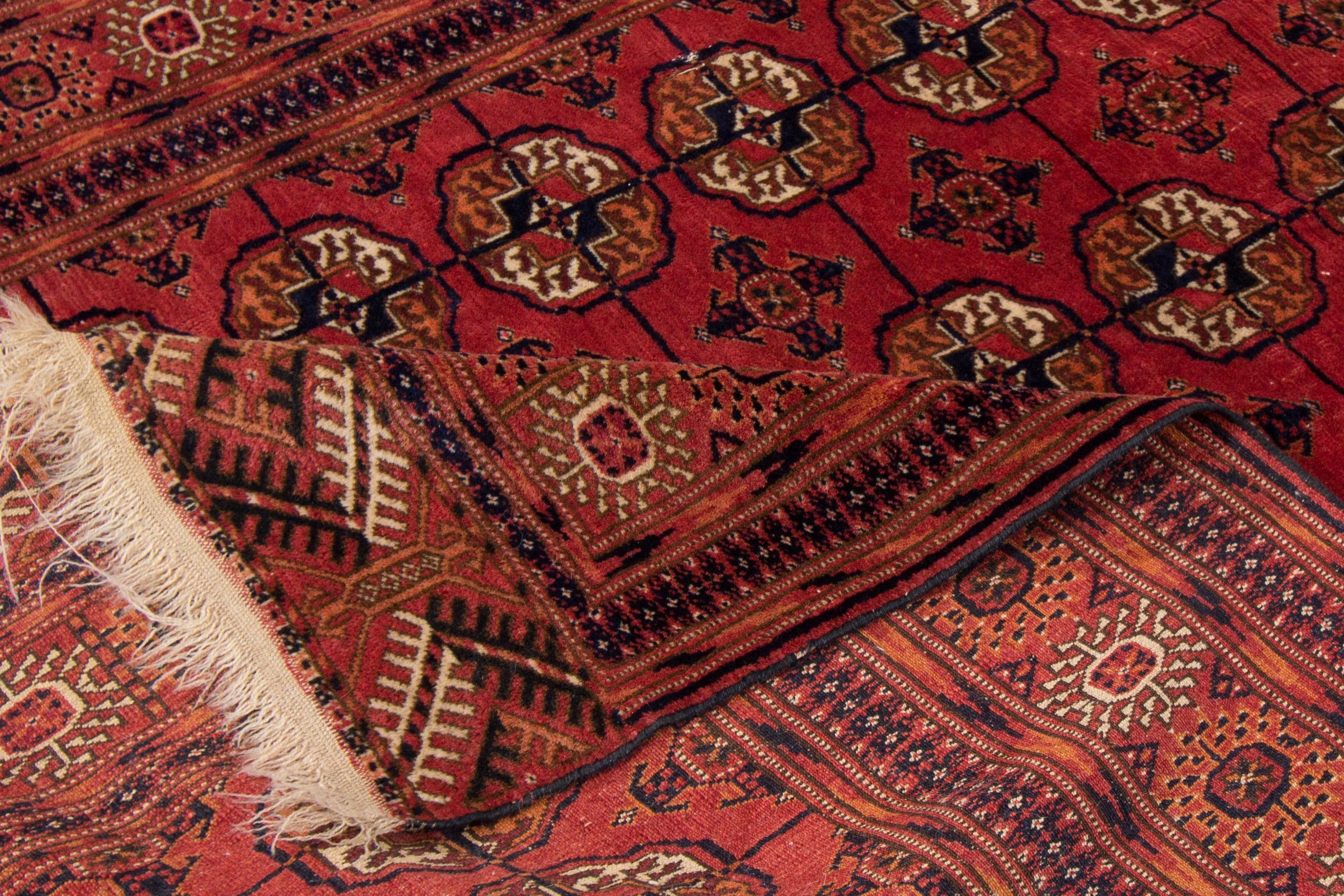 Magnifique tapis vintage turkmène en laine nouée à la main avec un champ rouge. Ce tapis persan présente des accents ivoire et bleu dans un magnifique motif géométrique.

Ce tapis mesure : 4'1
