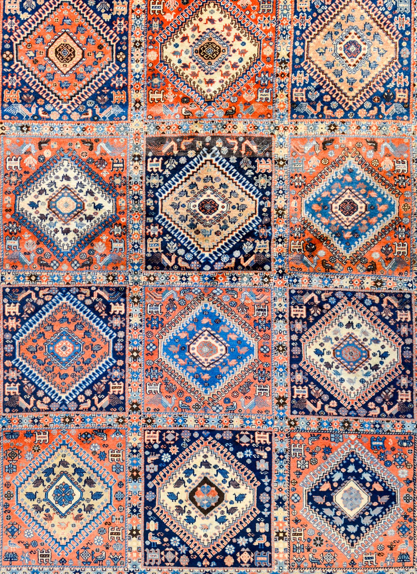 A beautiful vintage Persian Yalameh rug with grid of twelve diamond patterned motifs, each with myriad stylized flowers and animals woven in complimentary crimson, indigo, cream, and black vegetable dyed wool. The border is very complex with several