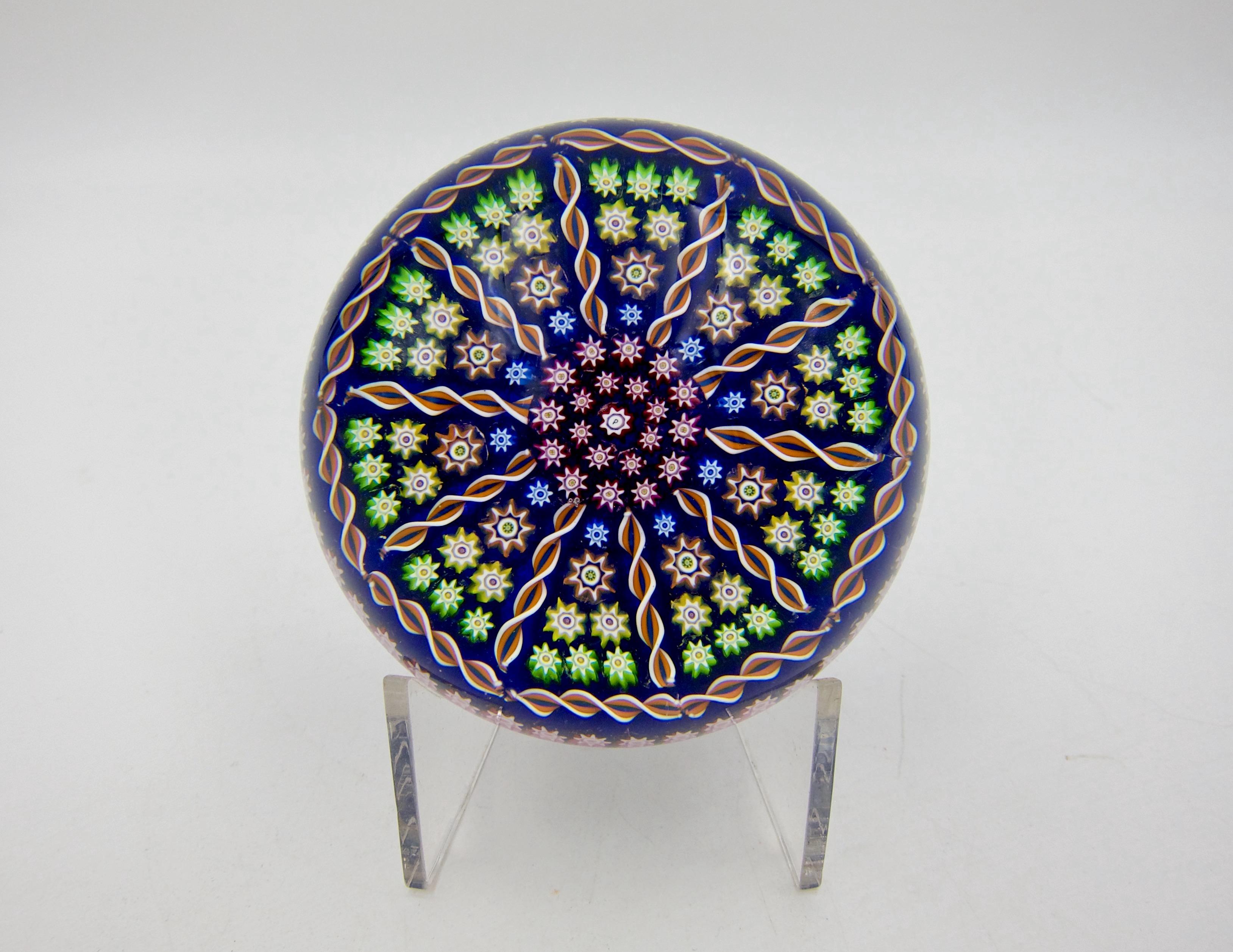 A vintage patterned millefiori and twist art glass paperweight, handcrafted in Crieff, Scotland at Perthshire Paperweights, Ltd., dating 1985-1997.  Designed in a 1-1-2-3 pattern of colorful millefiori canes separated by 10 spokes radiating from two