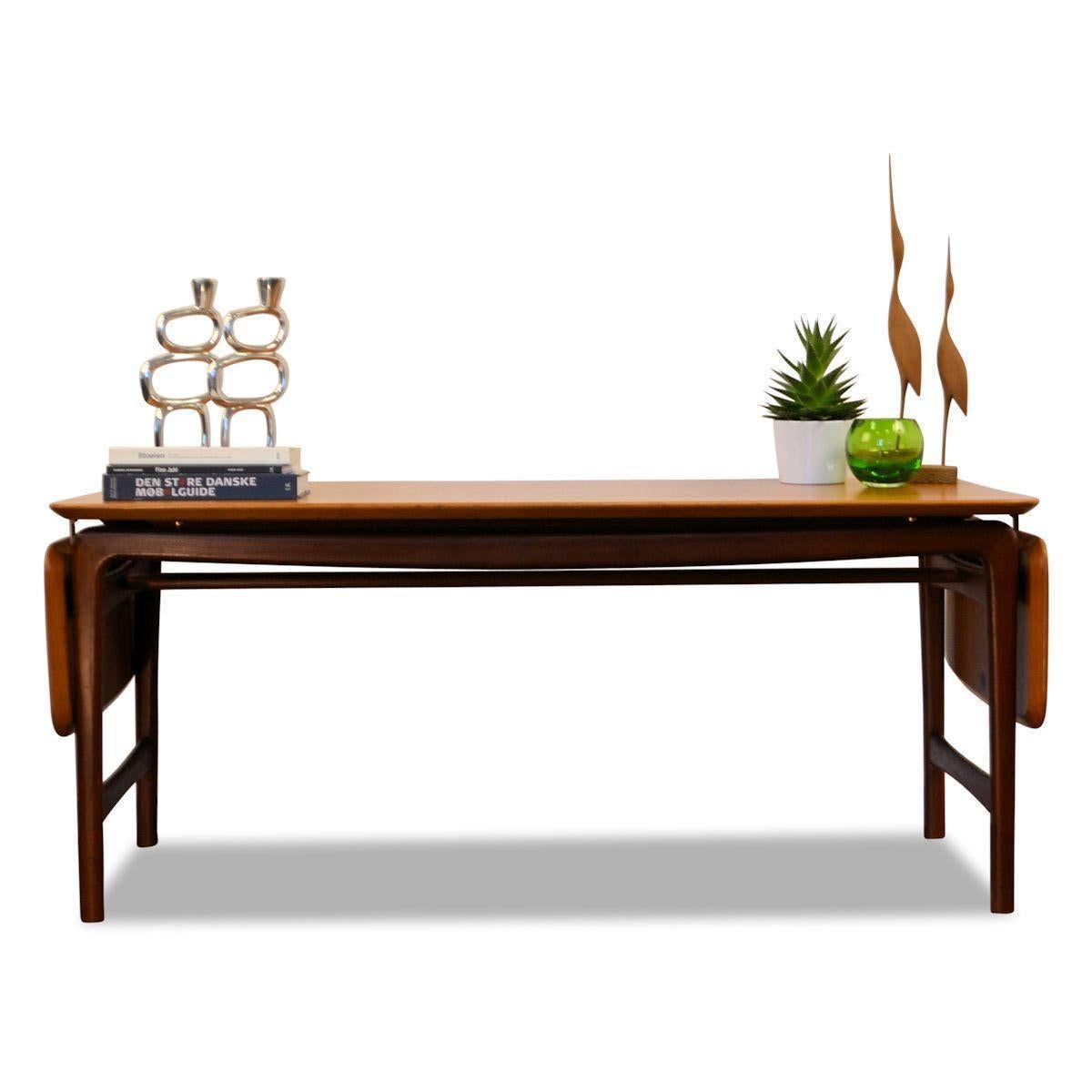 Vintage Danish design extendable massive teak table designed by Peter Hvidt & Orla Mølgaard-Nielsen for France & Daverkosen during the 1950s.
This coffee table is made from solid teak wood with foldable side leaves and brass hardware.