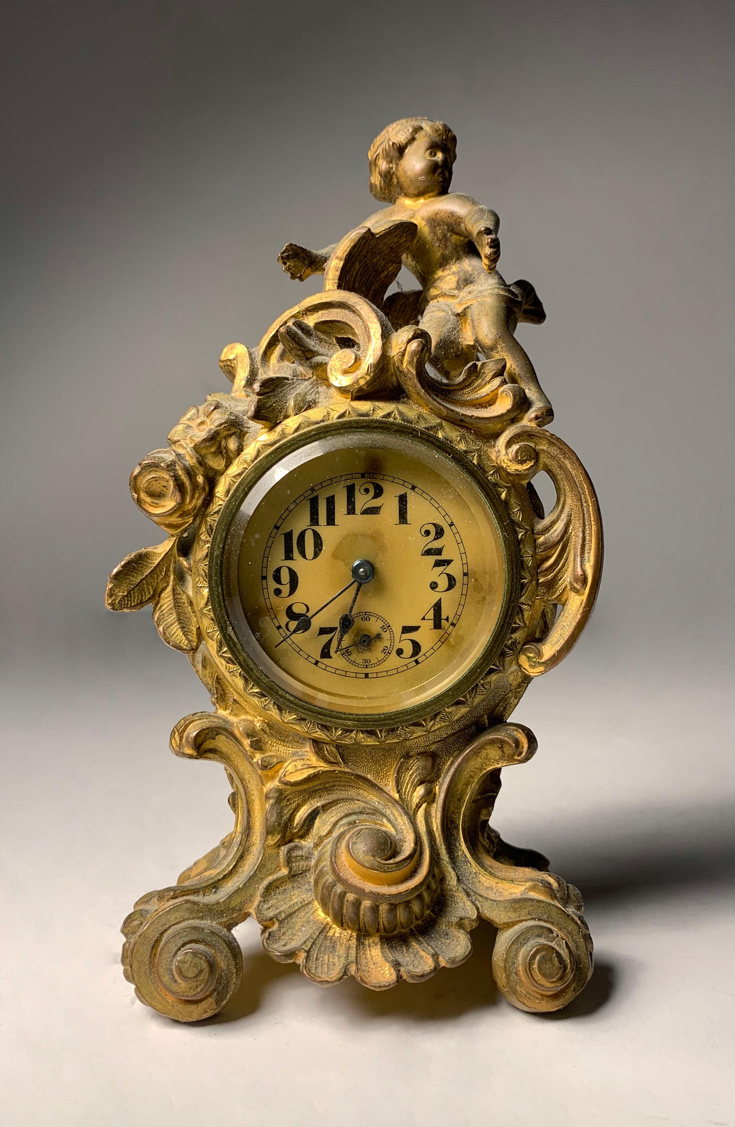 Adorable Petite French bronze Cherub clock. Uncertain to the exact age of the clock. I would estimate it to be from the early 20th century, but possibly late 19th century. 

Uncertain to whether the clock mechanism works or needs to be repaired or