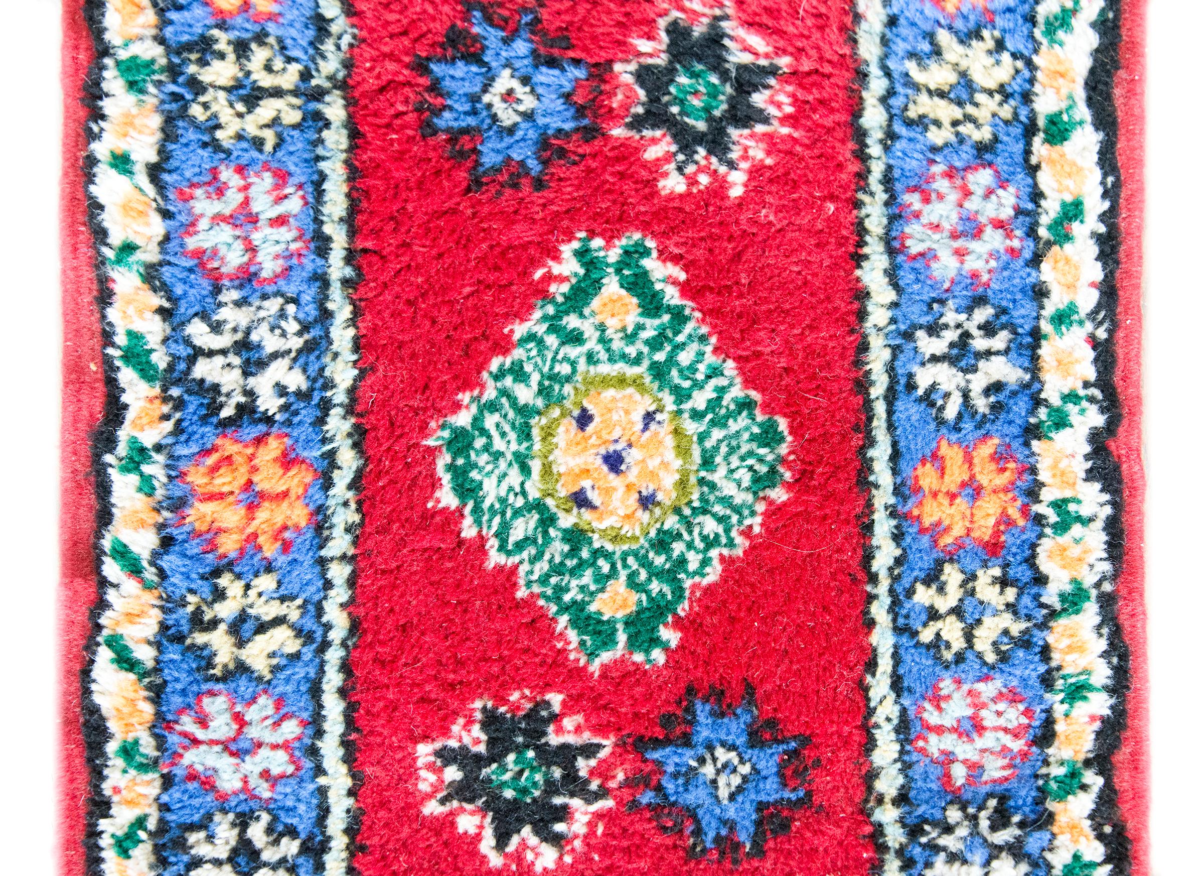 A vintage petite Moroccan rug with bold geometry and saturated color, woven with a large central green diamond medallion that floats confidently on a crimson ground. Surrounding the medallion are four stylized star motifs—simplified, graphic, and