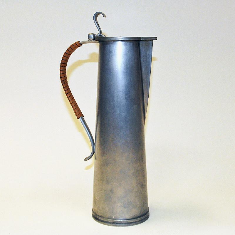 Lovely and classic Norwegian pewter jug/pitcher designed and made by Gunnar Havstad (b.1901 - d. 1973) from his own pewter workshop/studio in Nesodden (established 1928), Norway 1950s. A special design jug with leatherband wrapped handle and top lid