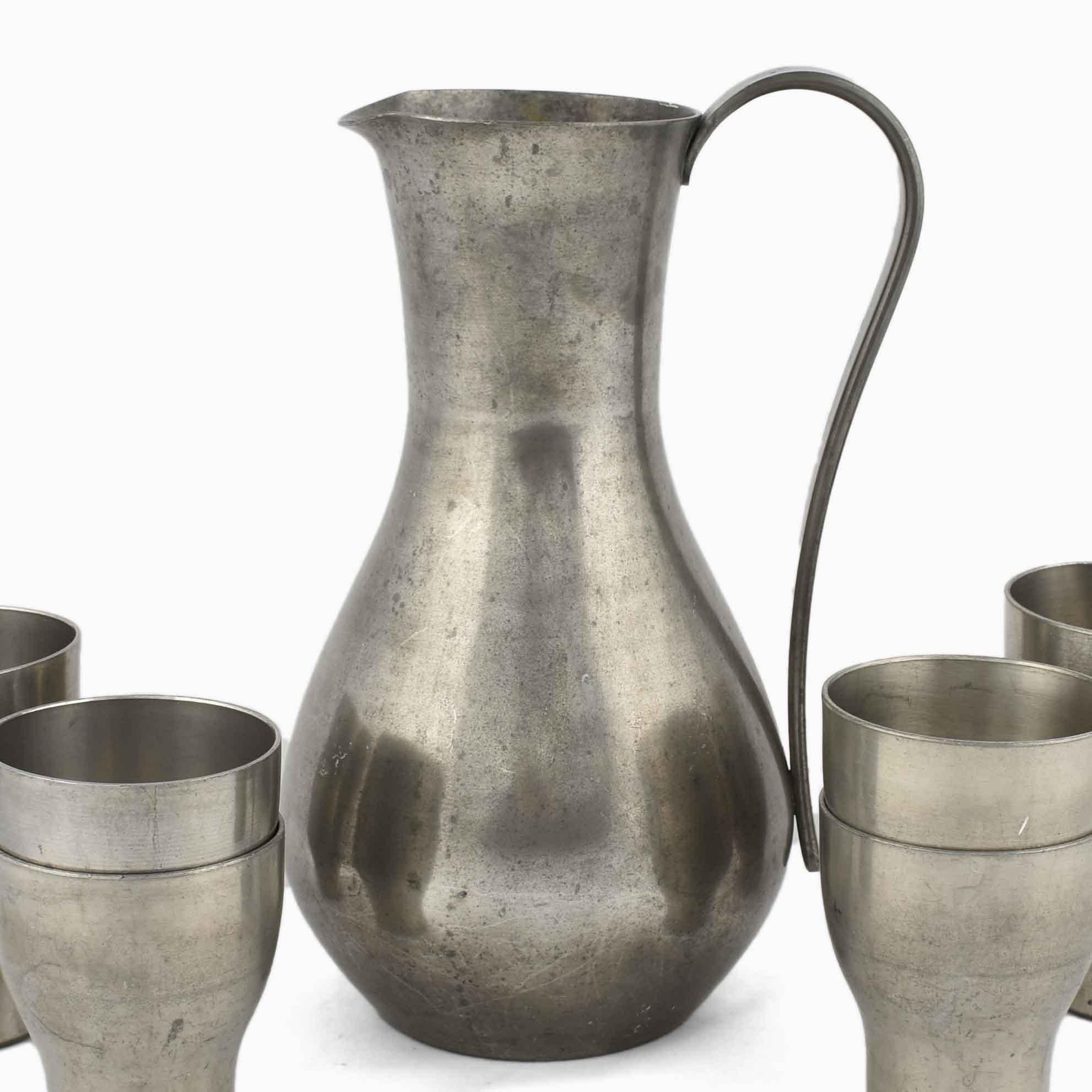 Pitcher with cups is an original decorative group of objects realized in the second third of the 20th century. 

Original Pewter.

Realized by Harald Buchrucker. Produced by Röders Factory. Made in Germany.

The set includes a pitcher and four