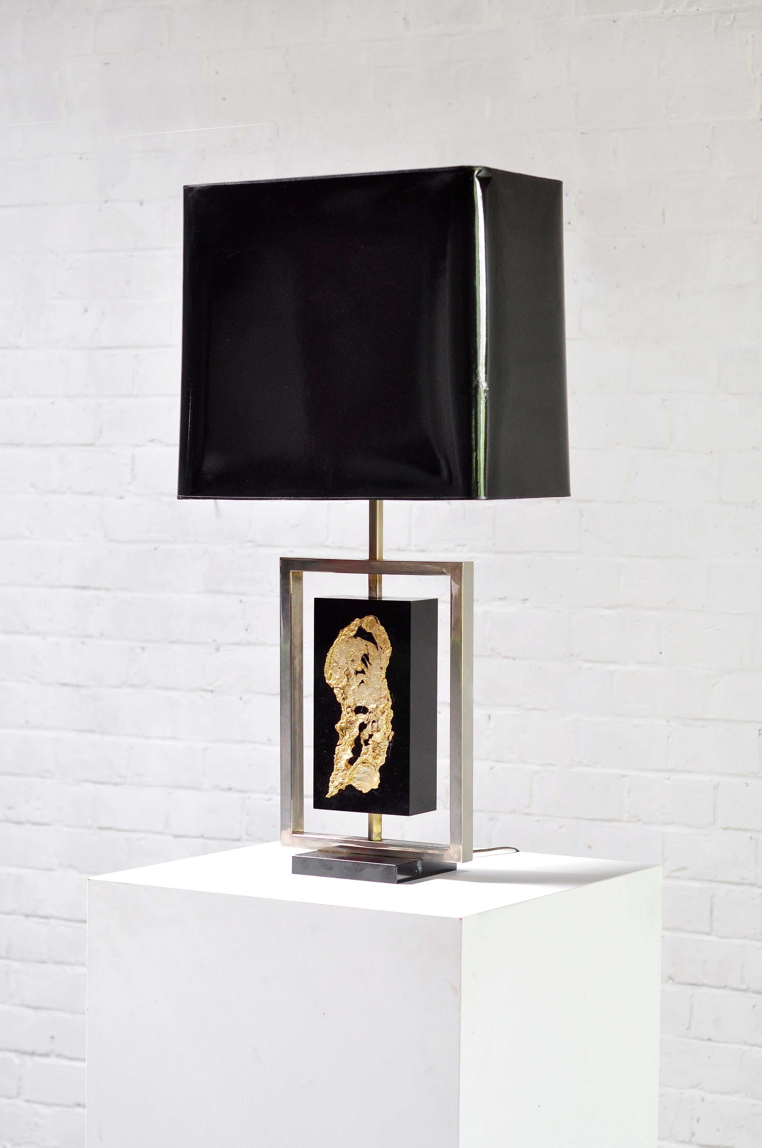 Une grande lampe de table caractéristique conçue par Philippe Cheverny, artiste et designer français à Paris dans les années 1970. Cette lampe présente une base en bois stratifié noir avec un cadre métallique et une décoration moderniste en métal