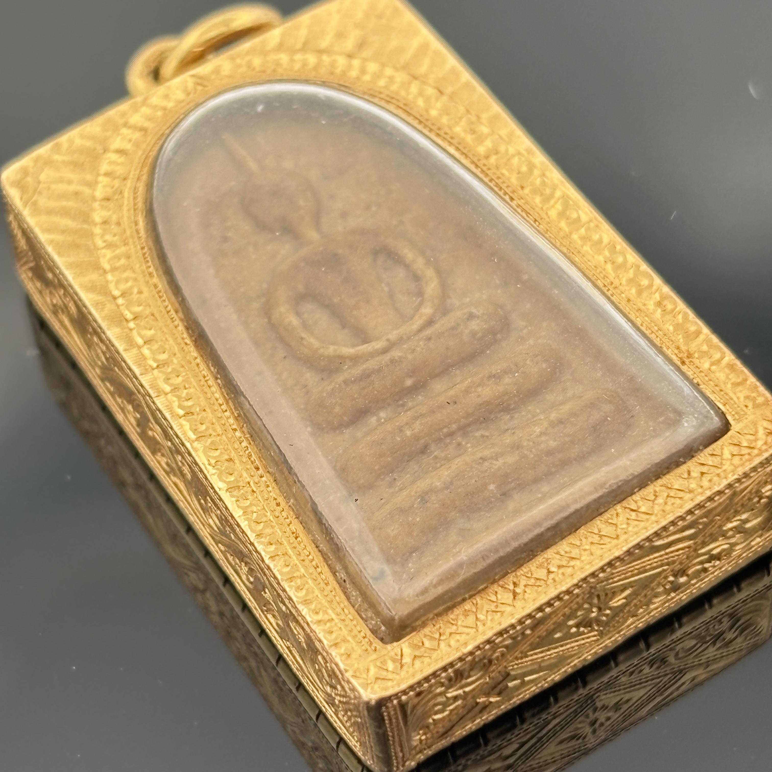 Une amulette bouddhiste Phra Somdej vintage dans un étui en or richement décoré, mêlant symbolisme spirituel et finesse d'exécution.

-Fabriqué en or massif 24K
-Mesure environ 7/8