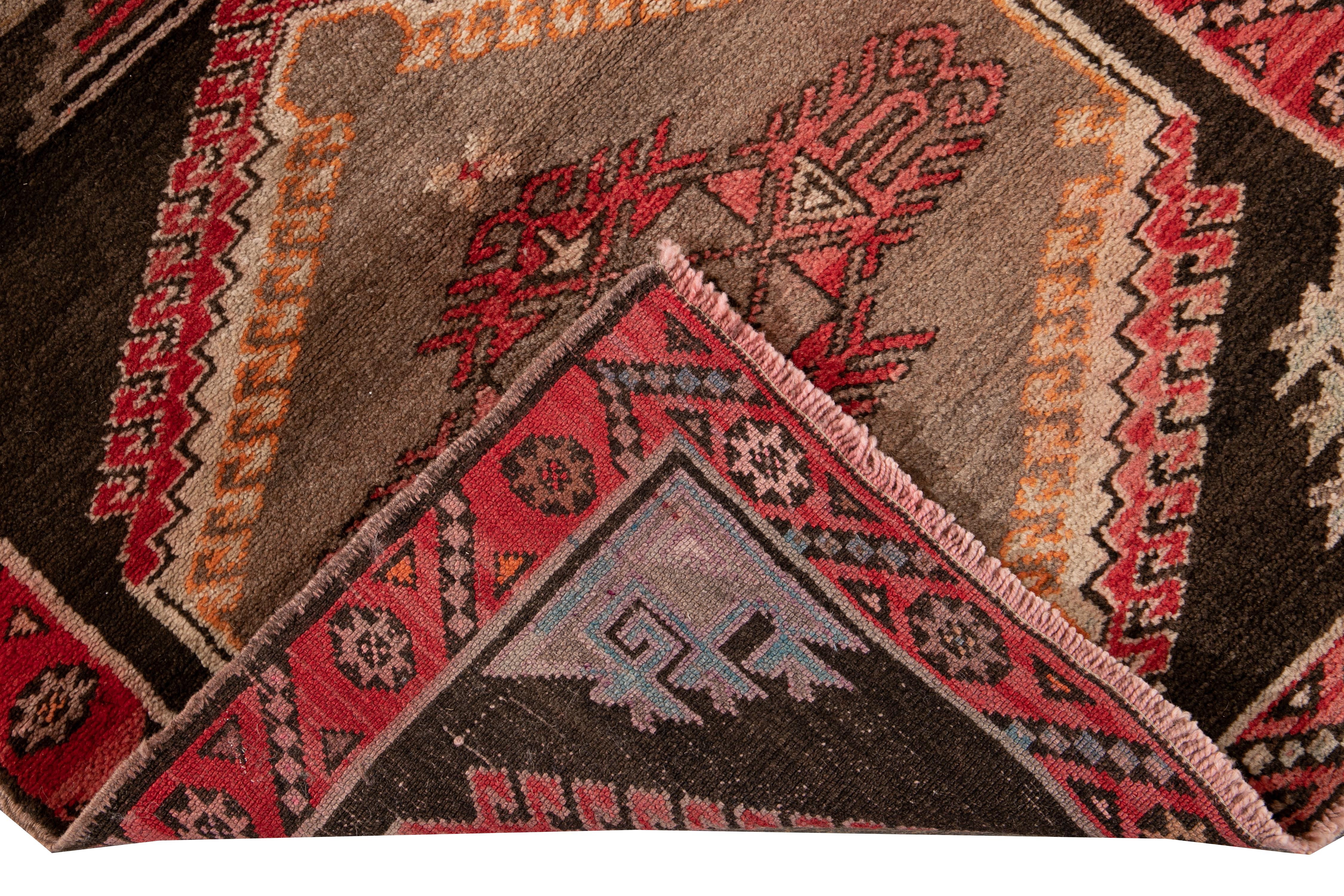 Beautiful Vintage pictorial Turkish hand knotted wool rug with a brown field. This Turkish rug has a red frame, and accents of orange and beige in a gorgeous all-over geometric pictorial design.

This rug measures 3' 3