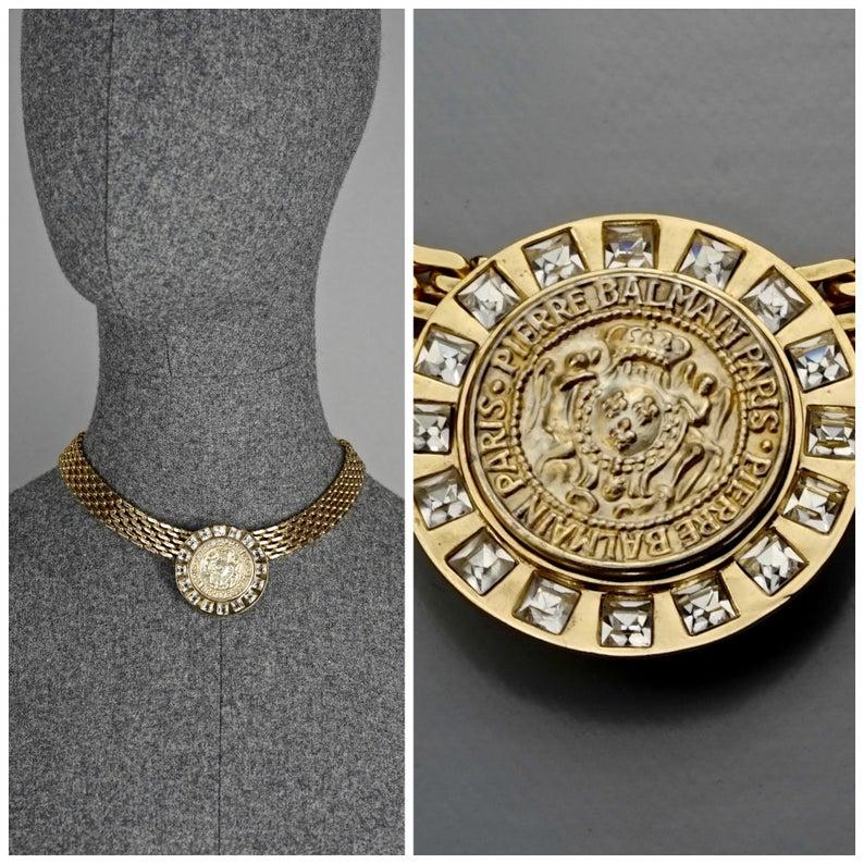 Vintage PIERRE BALMAIN Medallion Crest Rhinestone Necklace

Measurements:
Height: 2 5/8 inches
Wearable Length: 16 1/8 inches

Features:
- 100% Authentic PIERRE BALMAIN.
- Rustic medallion crest at the center with PIERRE BALMAIN PARIS