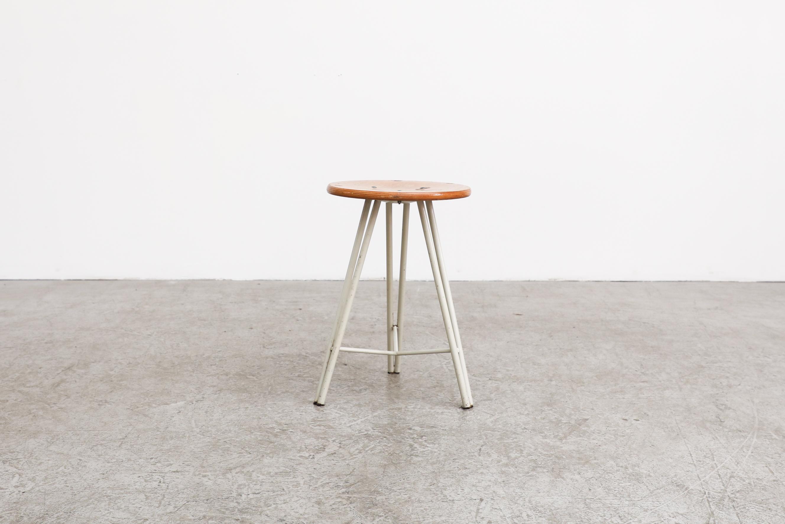 Little tripod task stool with white enameled legs with a plywood round seat. In original condition with visible wear, consistent with its age and use.