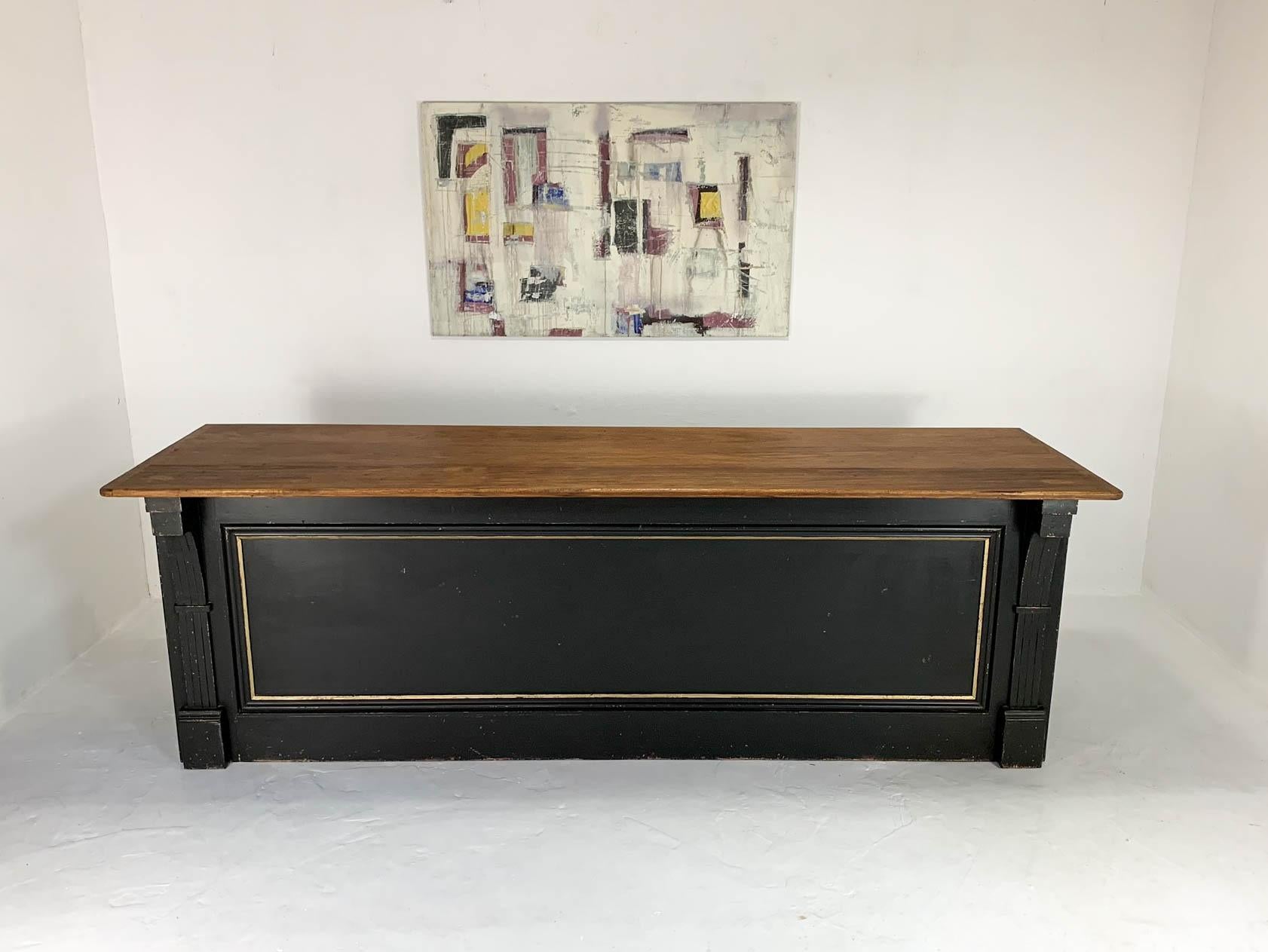Stunning pine shop counter that has been fully restored using reclaimed and some new materials. The counter has been painted black with gold to highlight the moldings on the paneled front. Corbels at either end enhance the decorative look of the