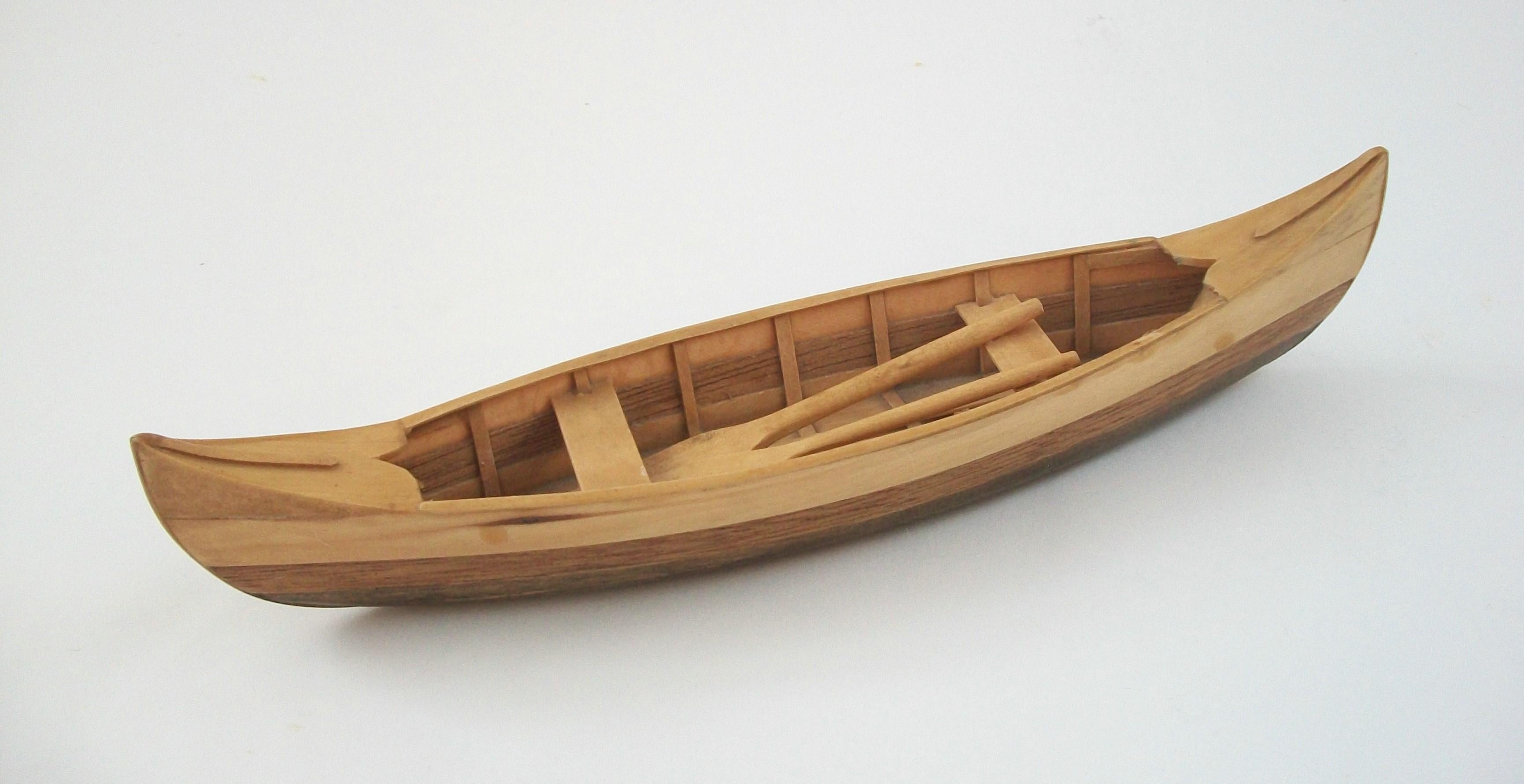 Vintage pine and cedar canoe scale model - featuring a detailed interior with two seats and fixed oars - the exterior base stained medium walnut, the cedar and pine left natural - unsigned - Canada (likely) - mid 20th century.

Excellent vintage