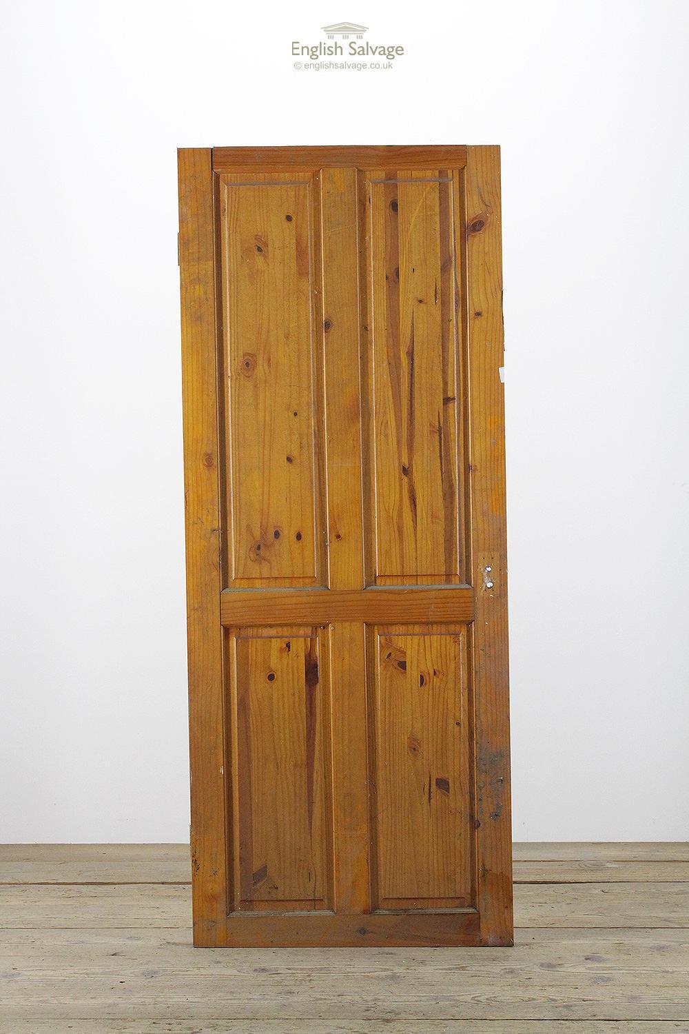 Reclaimed vintage varnished pine door with four raised panels. The door has been cut top and bottom, there is some separation at the top of the door plus lock, handle and nail holes.