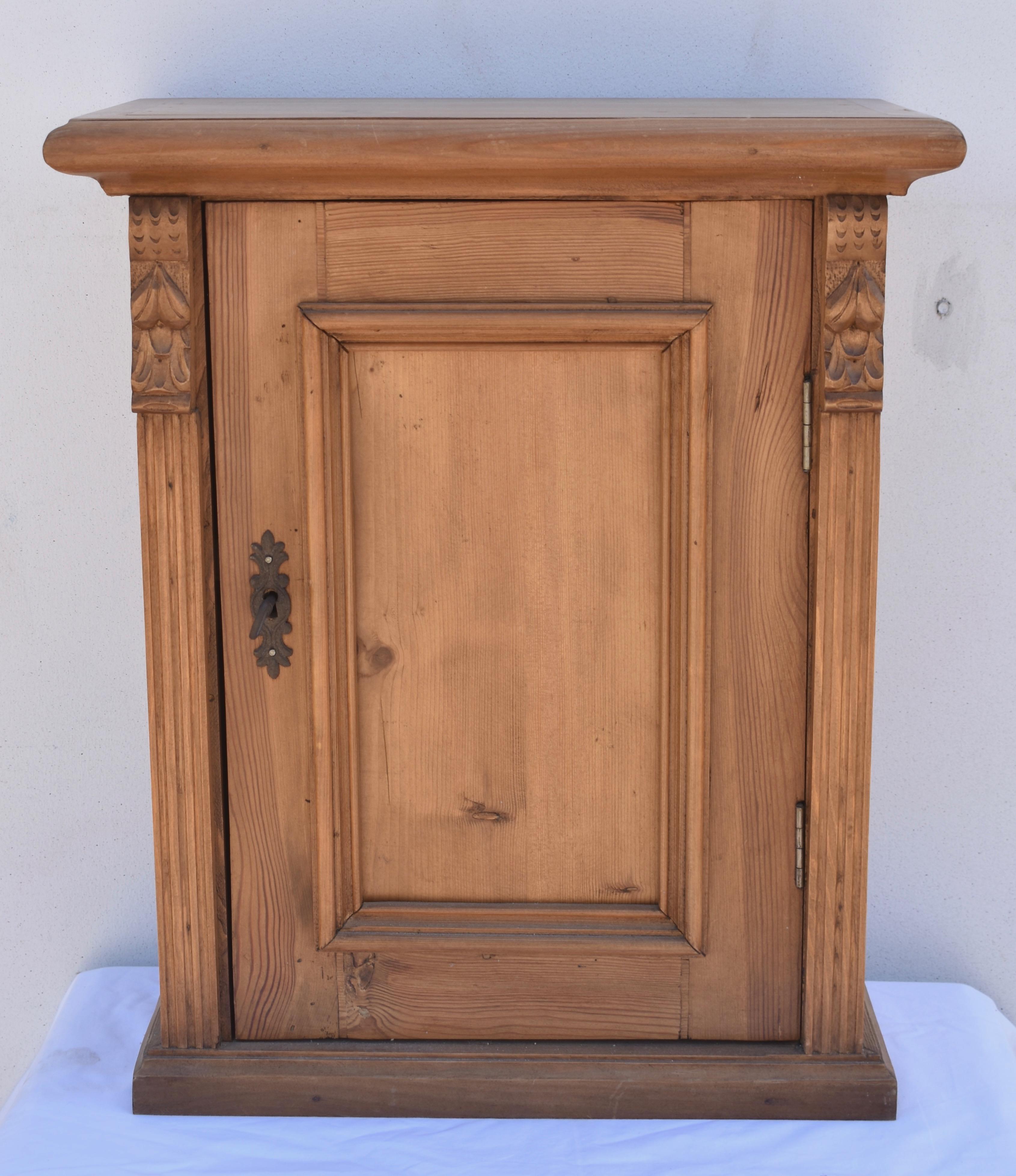 Antique pine hanging cupboards can be hard to find. This pretty little example is constructed from reclaimed pine and has the appearance and detail of an antique piece. The paneled door is flanked by applied fluting and attractive corbels and opens
