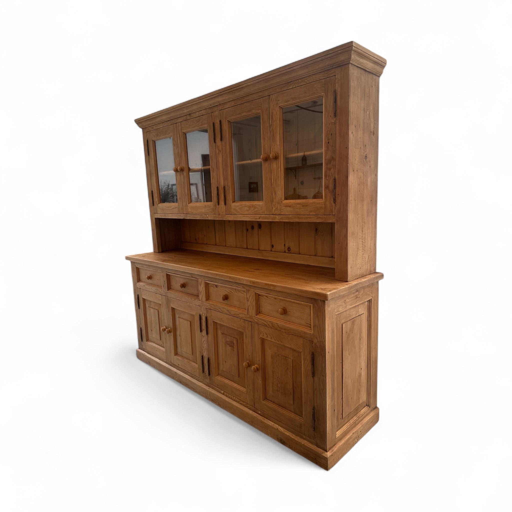 Questo mobile da cucina in pino vintage offre un ampio spazio di archiviazione con un classico fascino country. Con quattro armadietti superiori in vetro, spaziosi armadietti inferiori e un ampio spazio di lavoro sul bancone, è perfetto sia per