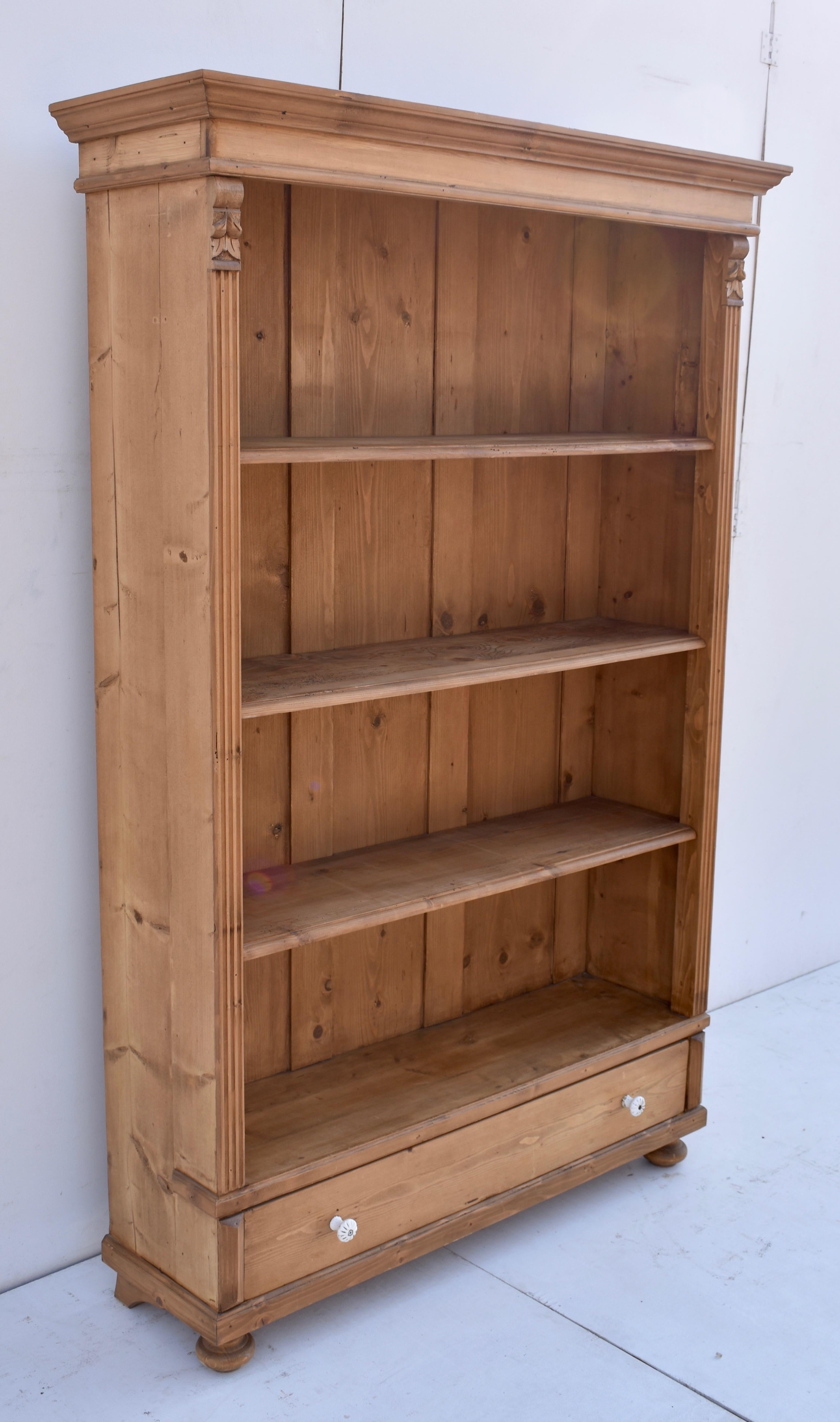 Antique pine bookcases are hard to find so the shell of this piece was provided by a vintage pine armoire which had suffered some damage or perhaps lost a door. With one board width removed from the sides and the original backboards and crown