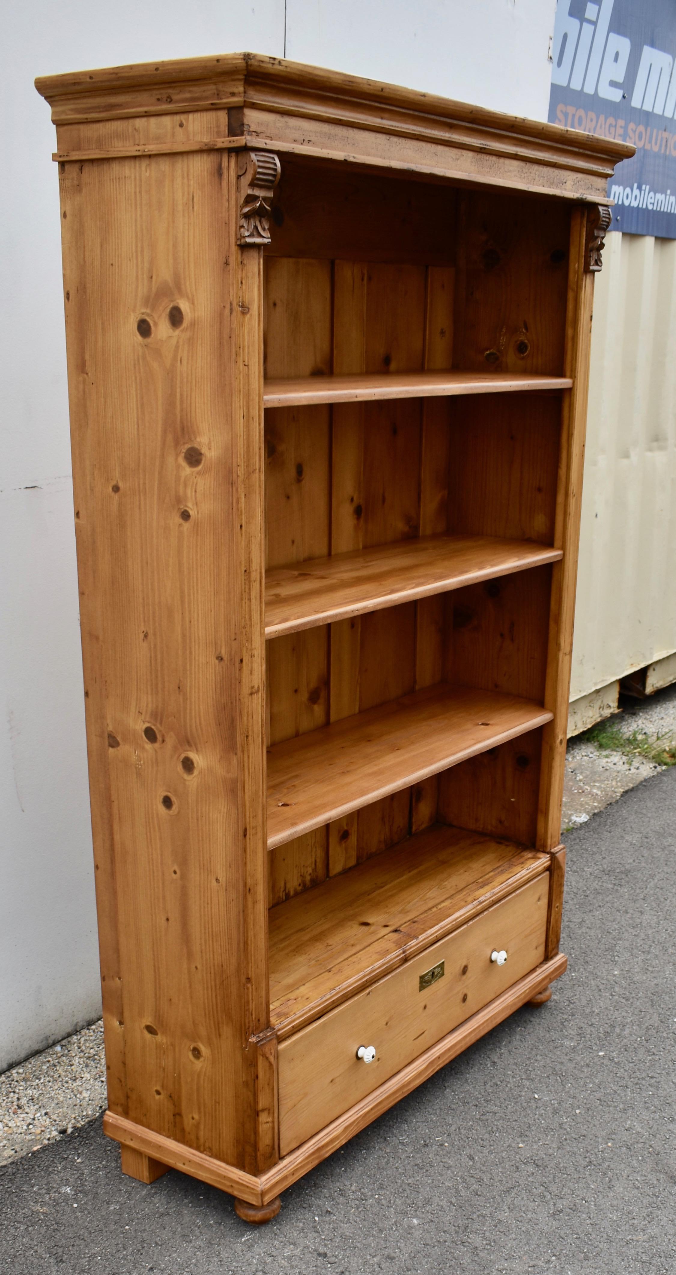 Antique pine bookcases are hard to find so the shell of this piece was provided by a vintage pine armoire. With one board width removed from the sides and the original backboards and crown molding retained, with the drawer reduced in depth, we get a