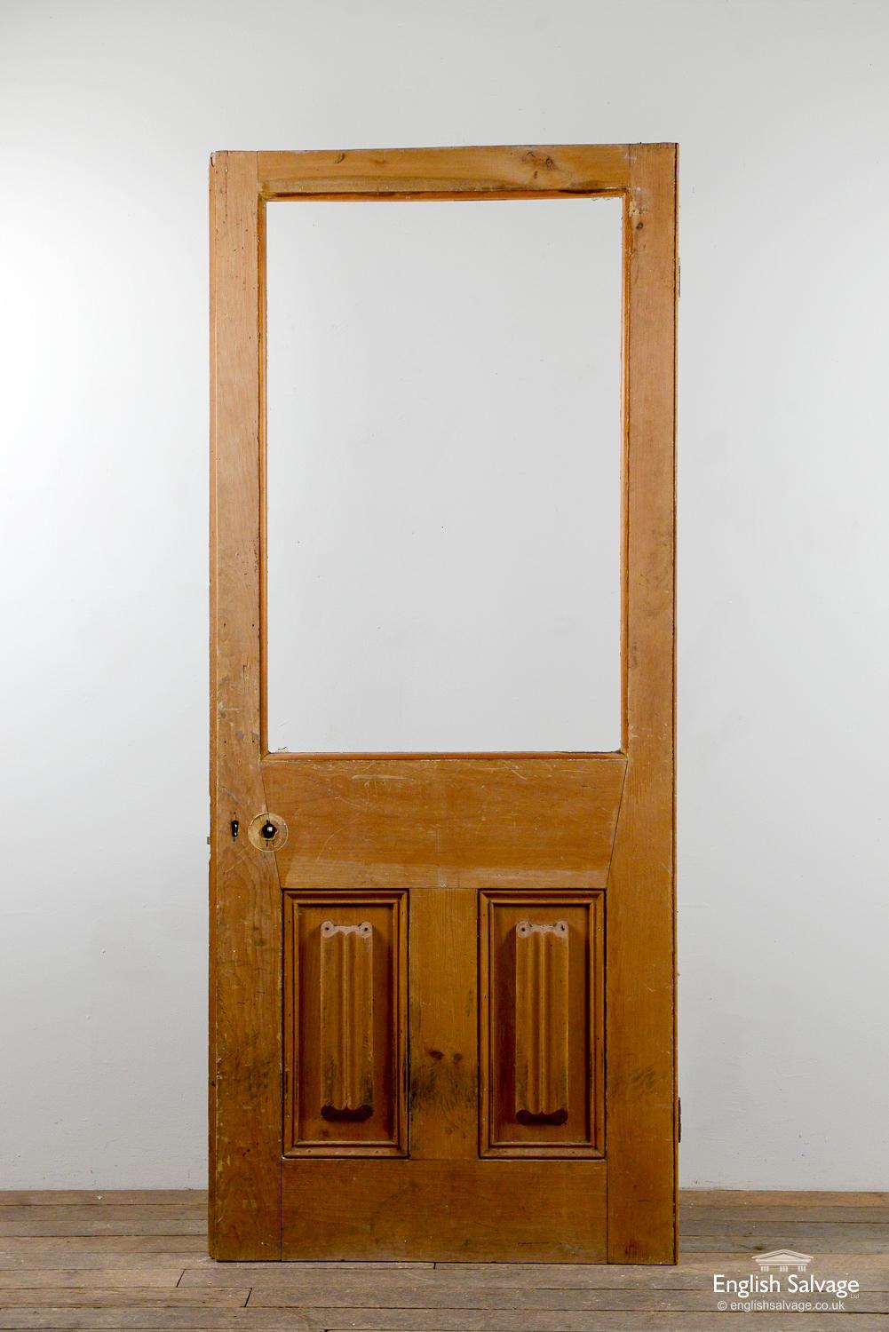 Reclaimed vintage pine door with a single panel for glass (none present) above two beaded panels, each with linenfold detailing to one side. The door has a beading strip to each side and a slightly protruding lip to the lock side. Old handle, lock