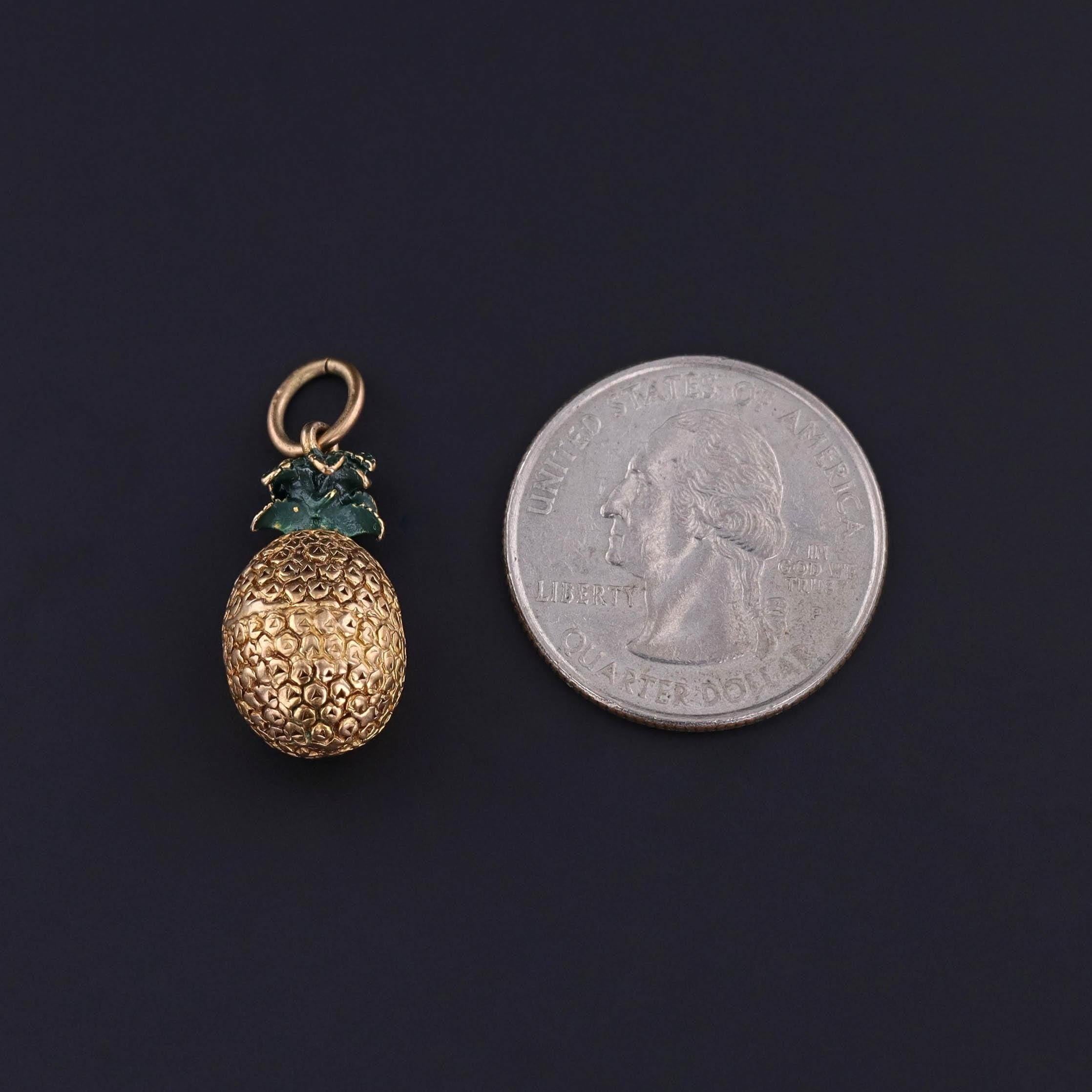 Breloque vintage en forme d'ananas : Cette breloque vintage (circa 1950-1960) représente un ananas en or 9ct, avec des feuilles en émail vert.

La pièce mesure 1,1 pouce du haut de l'anneau de saut à la base, 0,45 pouce de large et pèse 4,4 grammes.