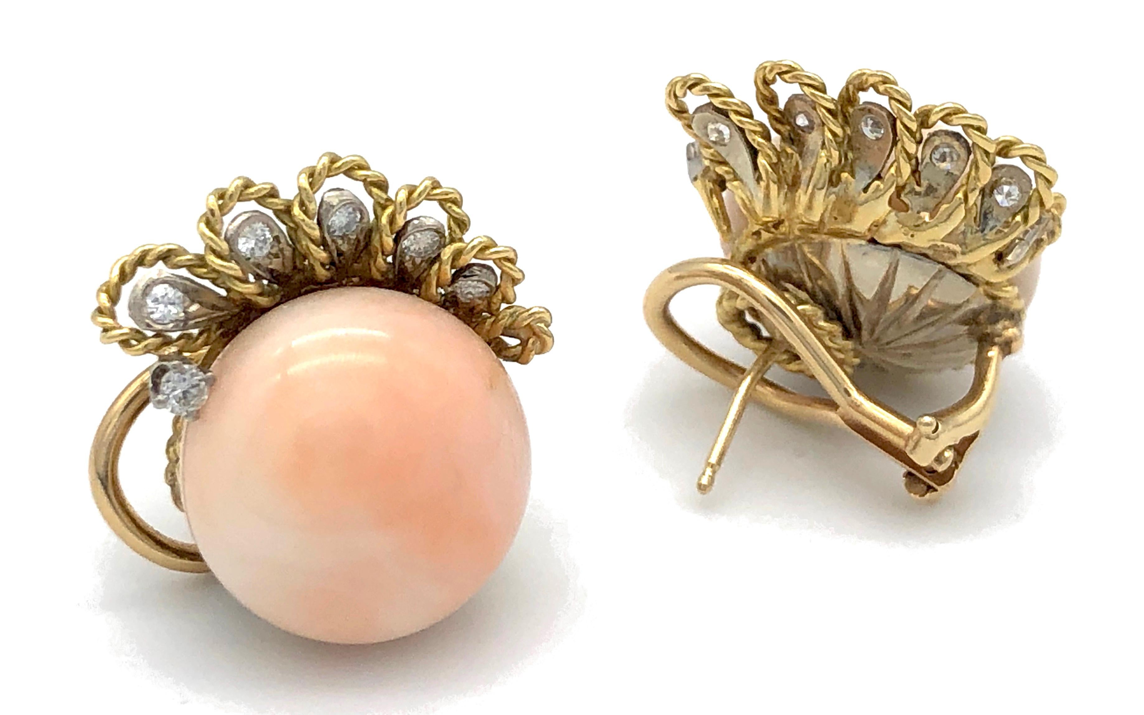 This pair of earclips features wonderful pink coral boutons mounted on 18k gold. 
Each clip is decorated with six platinum mounted diamonds, five diamonds are surrounded by loops made of twisted gold wire.
At the moment one of the clips has a stud