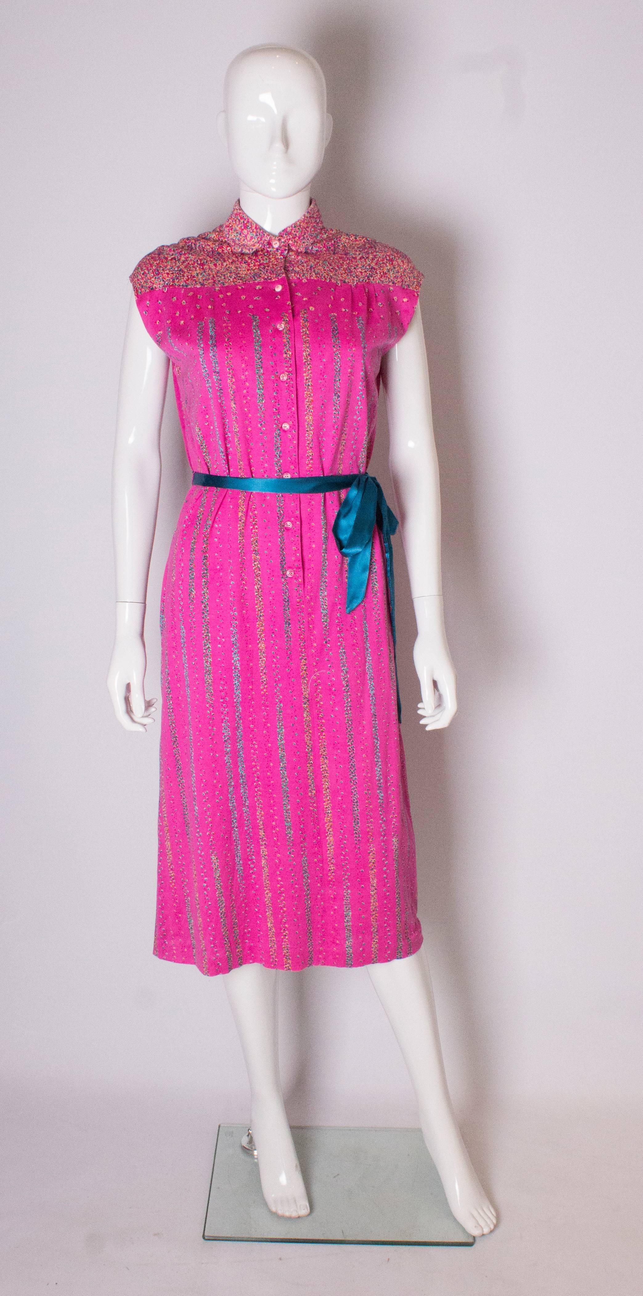 A pretty vintage pink cotton day dress by Fink. The dress has a printed collar and yoke, with an 8 button front opening, pockets on either side and belt hoops. It is fully lined.
