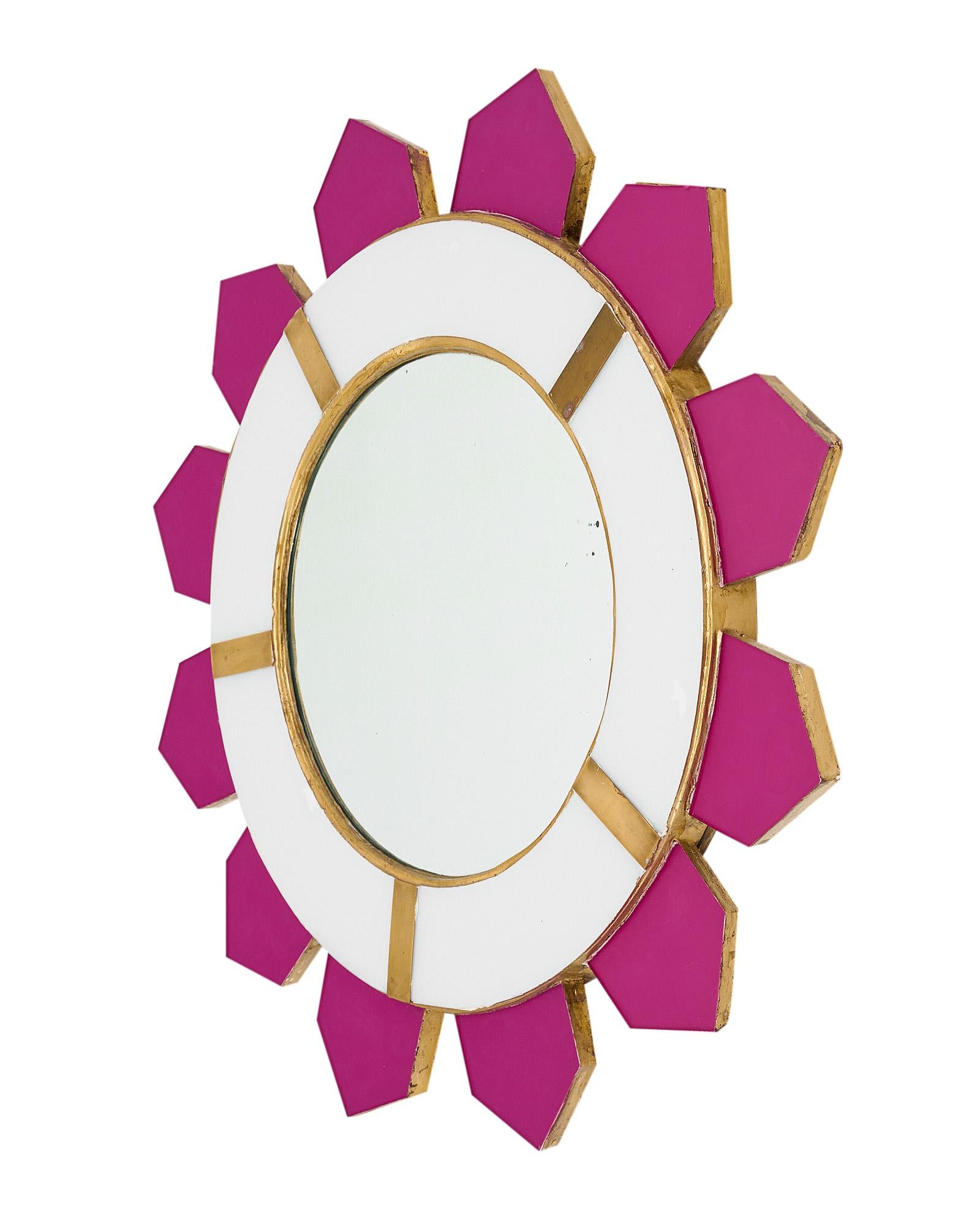 Modernist sunburst with a wooden structure and pink glass veneered rays emanating from a central circular mirror. The central mirror is framed with white glass elements as well as brass décor. We love the strong stylized concept of this piece.

