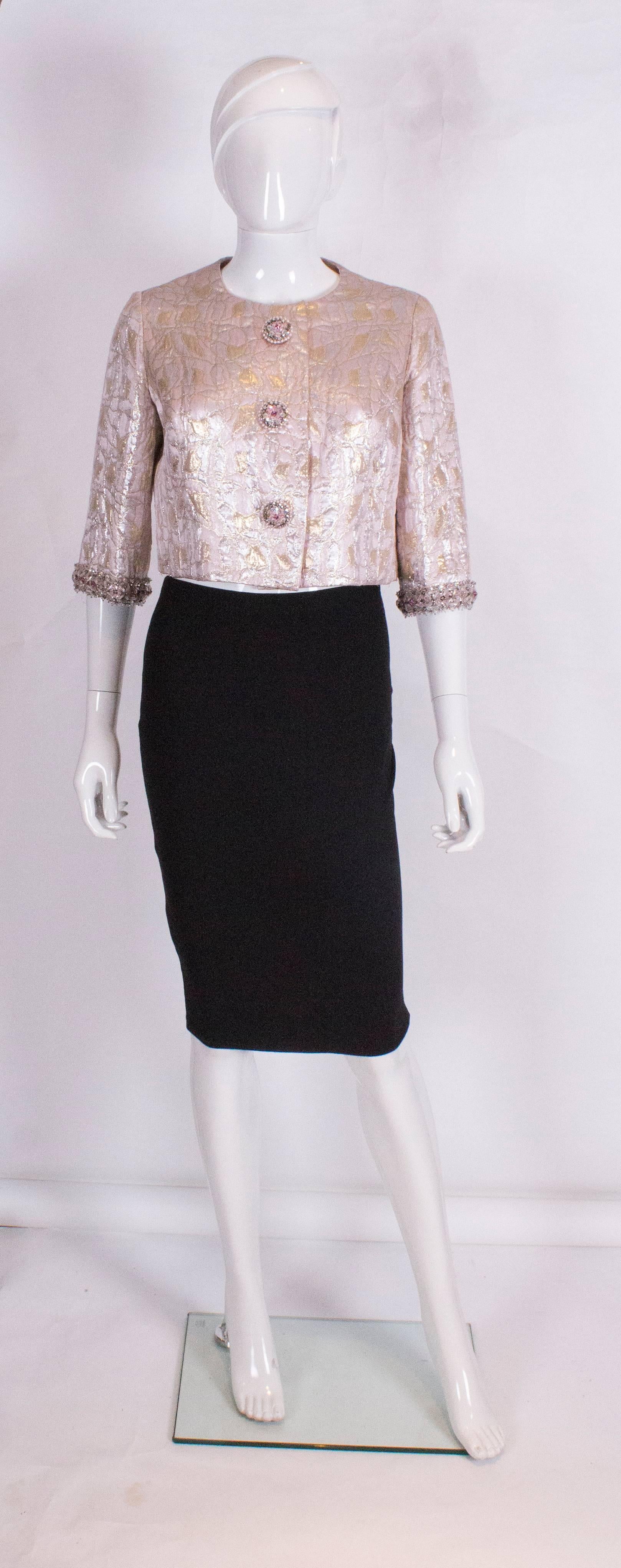 A charming and chic evening jacket by Neymar Couture of 19 Berkeley Street, London W1. The jacket hangs beautifully ( has weights in the hem),has elbow length sleeves and wonderful trim along the cuffs, and fastens with three decorative buttons.