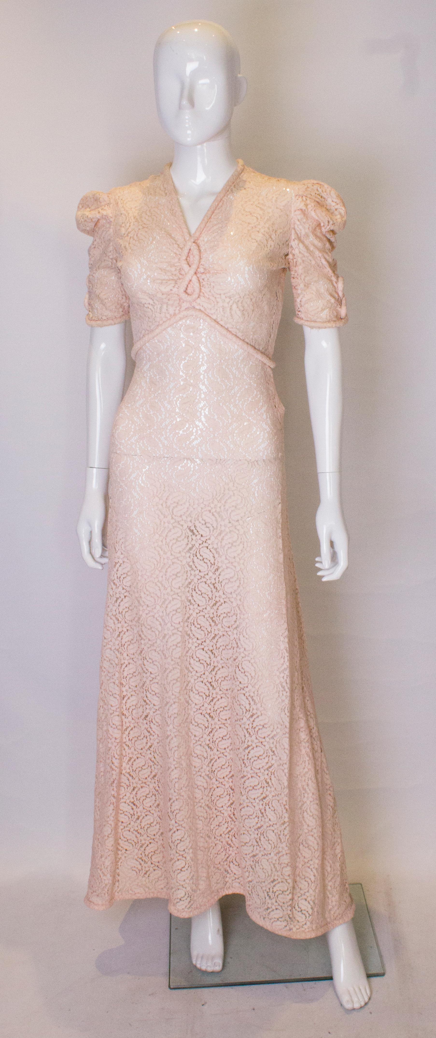 A stunning vintage pink lace gown, ideal for a bride or summer ball.
The dress dates from the 1930/40s, and has wonderful padding around the hem , cuffs, waist and neckline.  The dress has short sleeves with gathering at the shoulders,  a v neckline