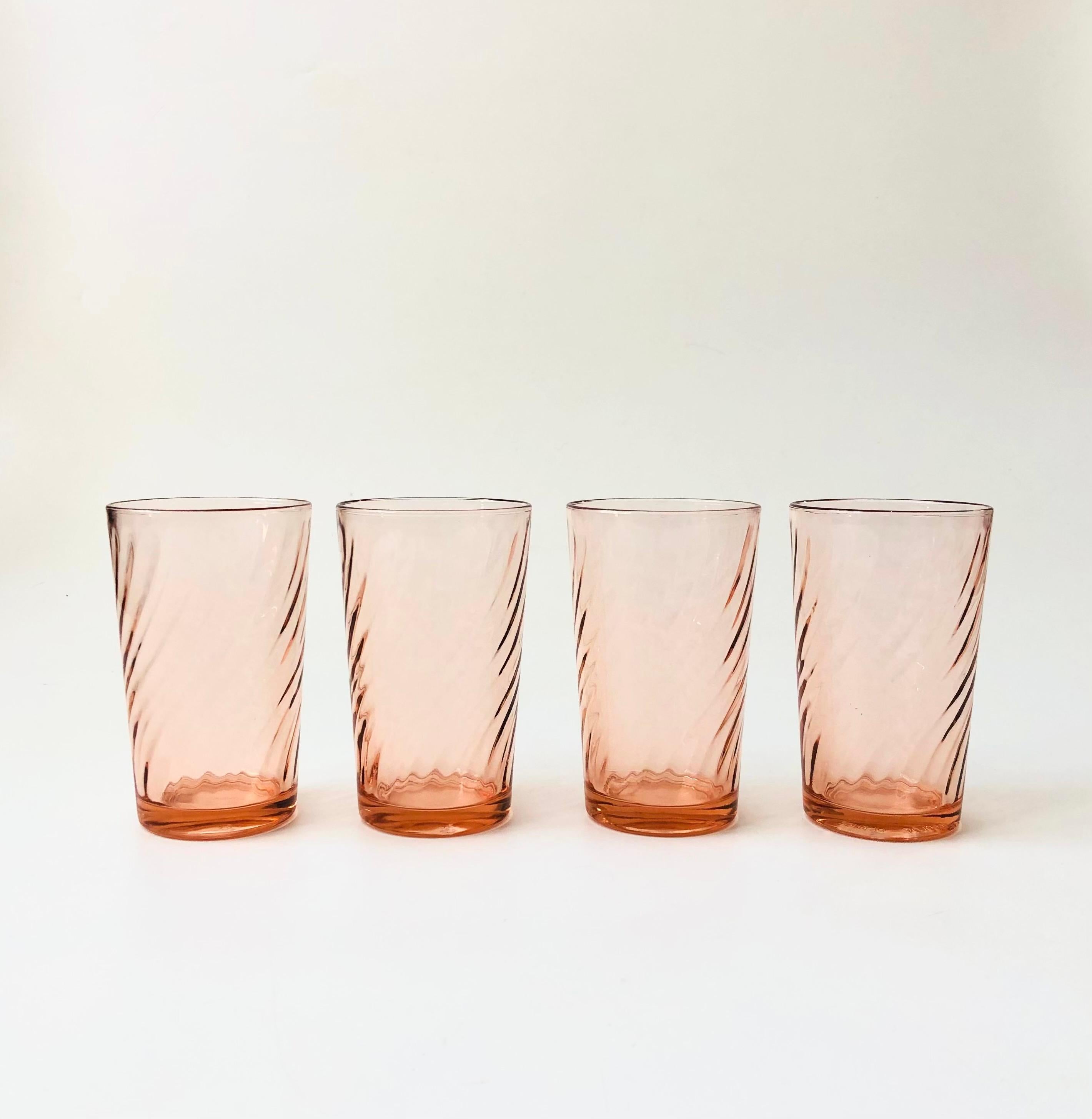 A set of 4 vintage tall glasses in a pale blush pink hue. Each glass has a lovely swirl design. Perfect for using as water glasses or for cocktails. Made in France by Arcoroc.

