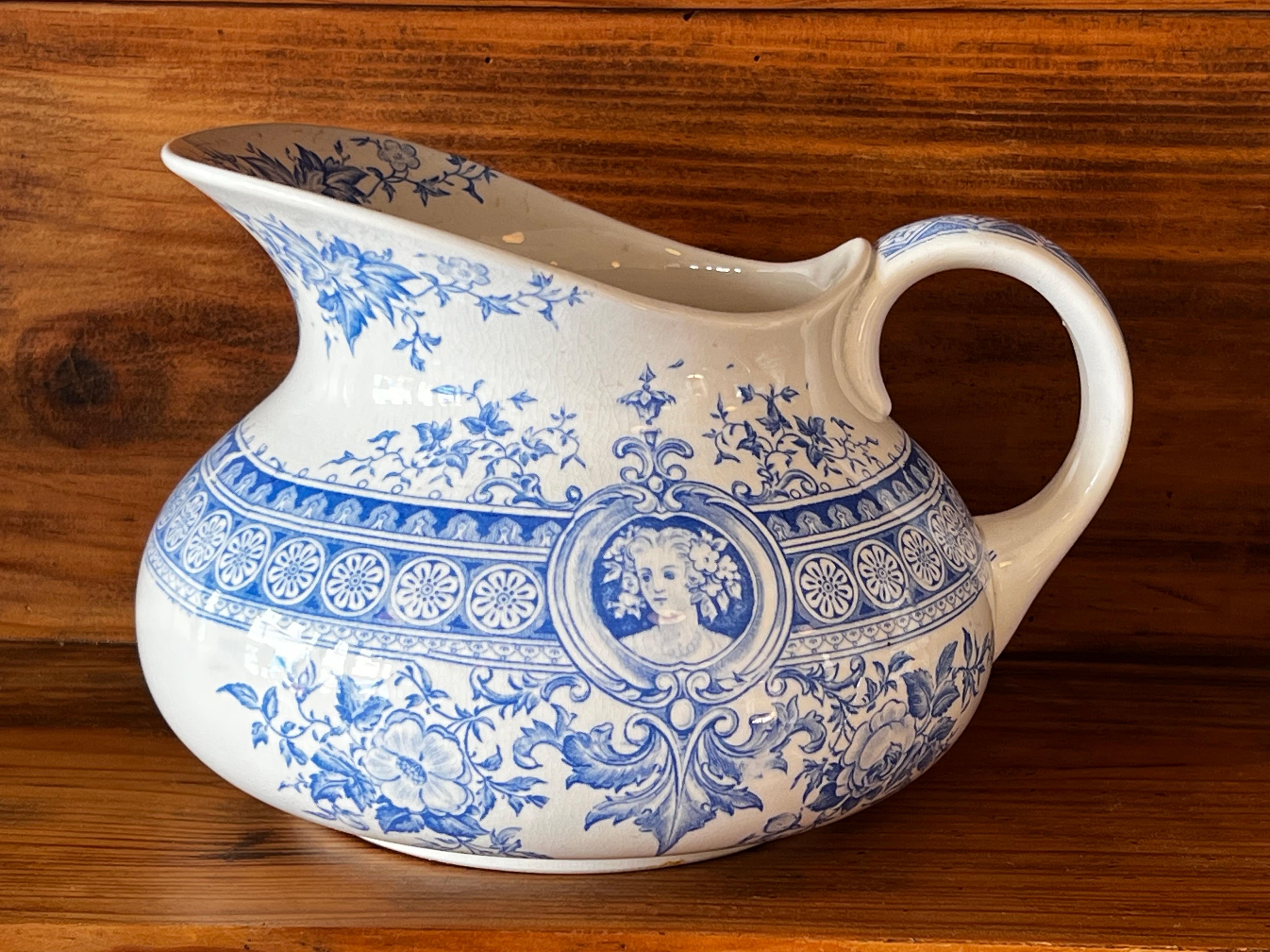Dieser Waschkrug stammt ursprünglich aus der Fabrik von Sarreguemines in Ostfrankreich. Das Parisia-Muster wurde 1895, Ende des 19. Jahrhunderts, entwickelt. Der Krug ist mit zarten Blumenmotiven und einem beidseitigen Medaillon verziert, das ein