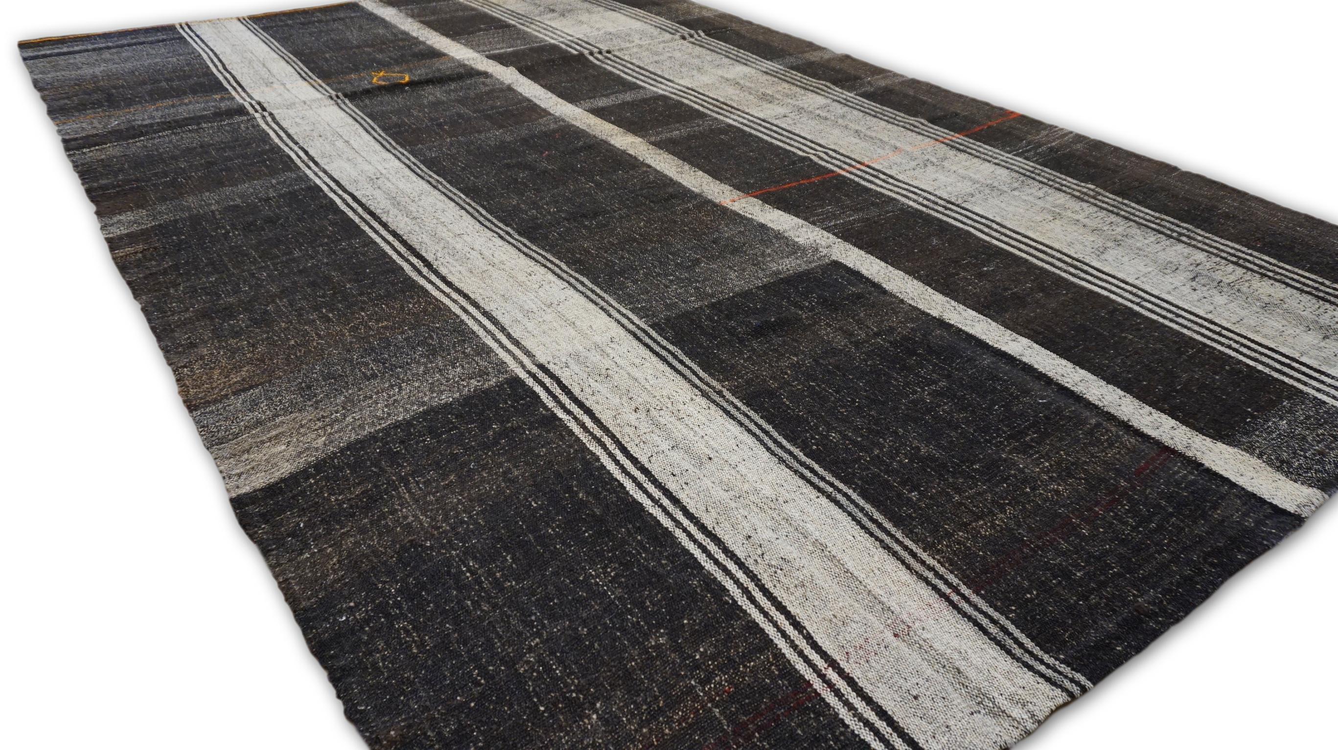 Ce kilim vintage présente un design saisissant inspiré des carreaux dans des tons contrastés gris, marron, anthracite et neutres. Tissé avec un équilibre méticuleux de lignes structurées et d'irrégularités naturelles, cette pièce incarne l'artisanat