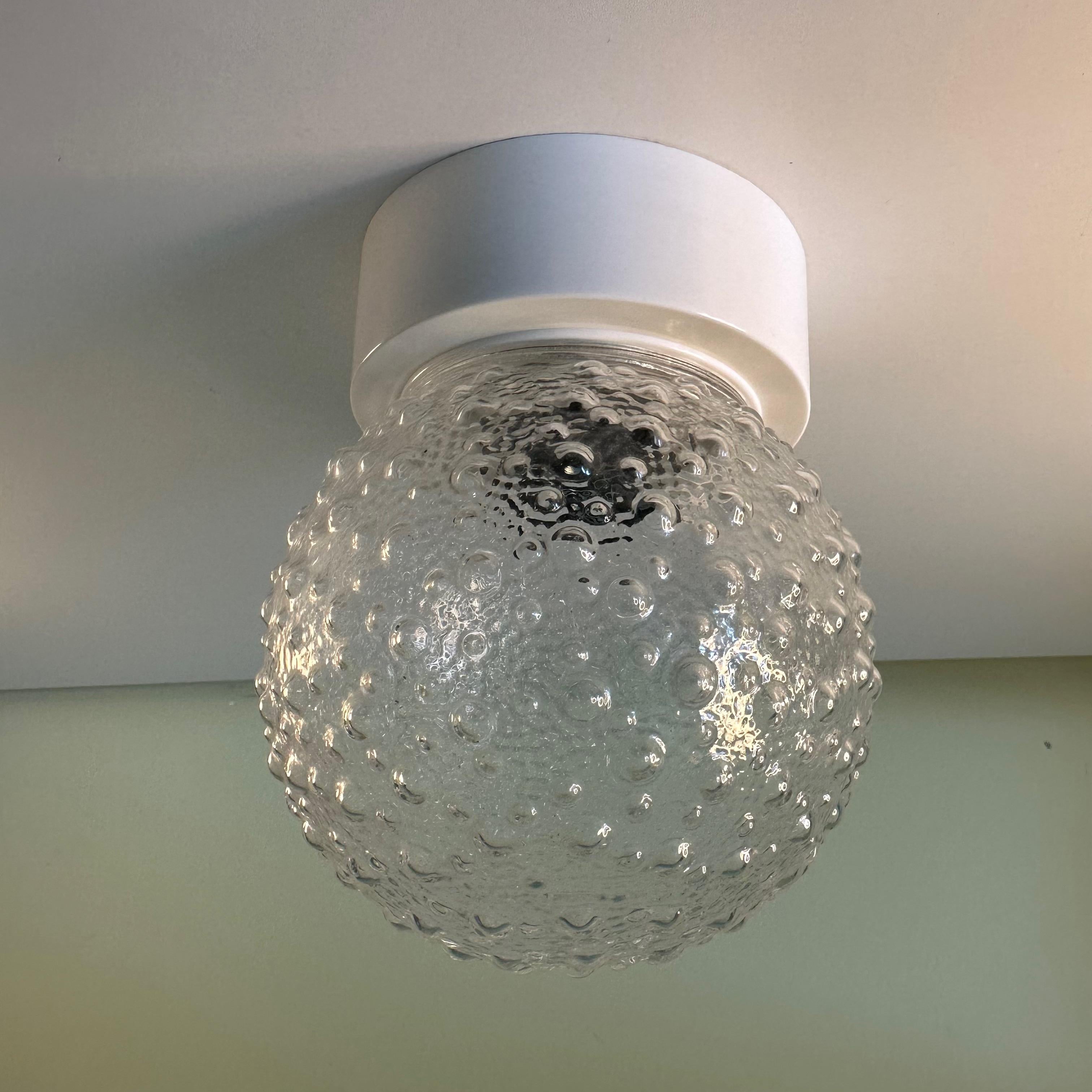 Small Vintage clear and white plastic bubble textured globe flush mount lamp or wall light sconce. This is a small and charming lamp fixture with a space age vibe is a 2 part light comprised of a clear spherical plastic globe molded with a dotted,