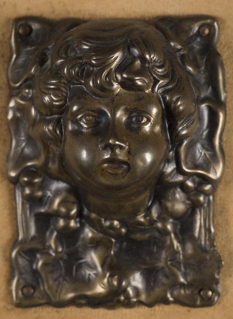 Cette plaque vintage est un très élégant objet décoratif en bronze réalisé vers 1910 par un artiste anonyme.
Les petites assiettes représentent des figures de jeunes garçons et des feuilles de lierre entourées d'un cadre en bois.

Cet objet est