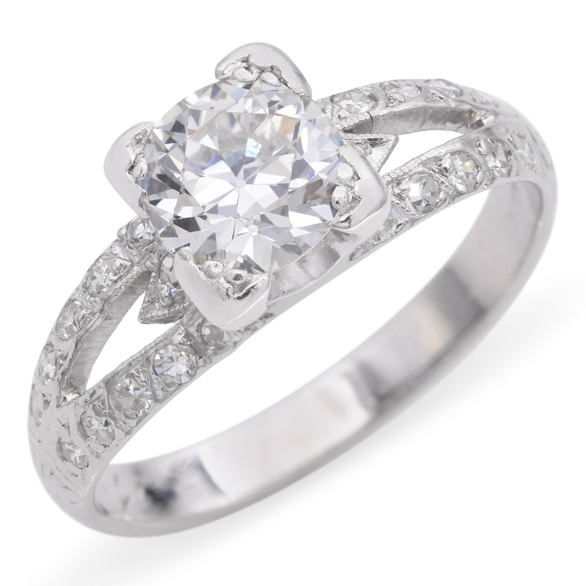 Crafted in lustrous platinum, this ring features a stunning round-cut central stone that sparkles brilliantly. The band is adorned with a series of smaller stones, intricately set along the split shank, enhancing the overall elegance of the piece.