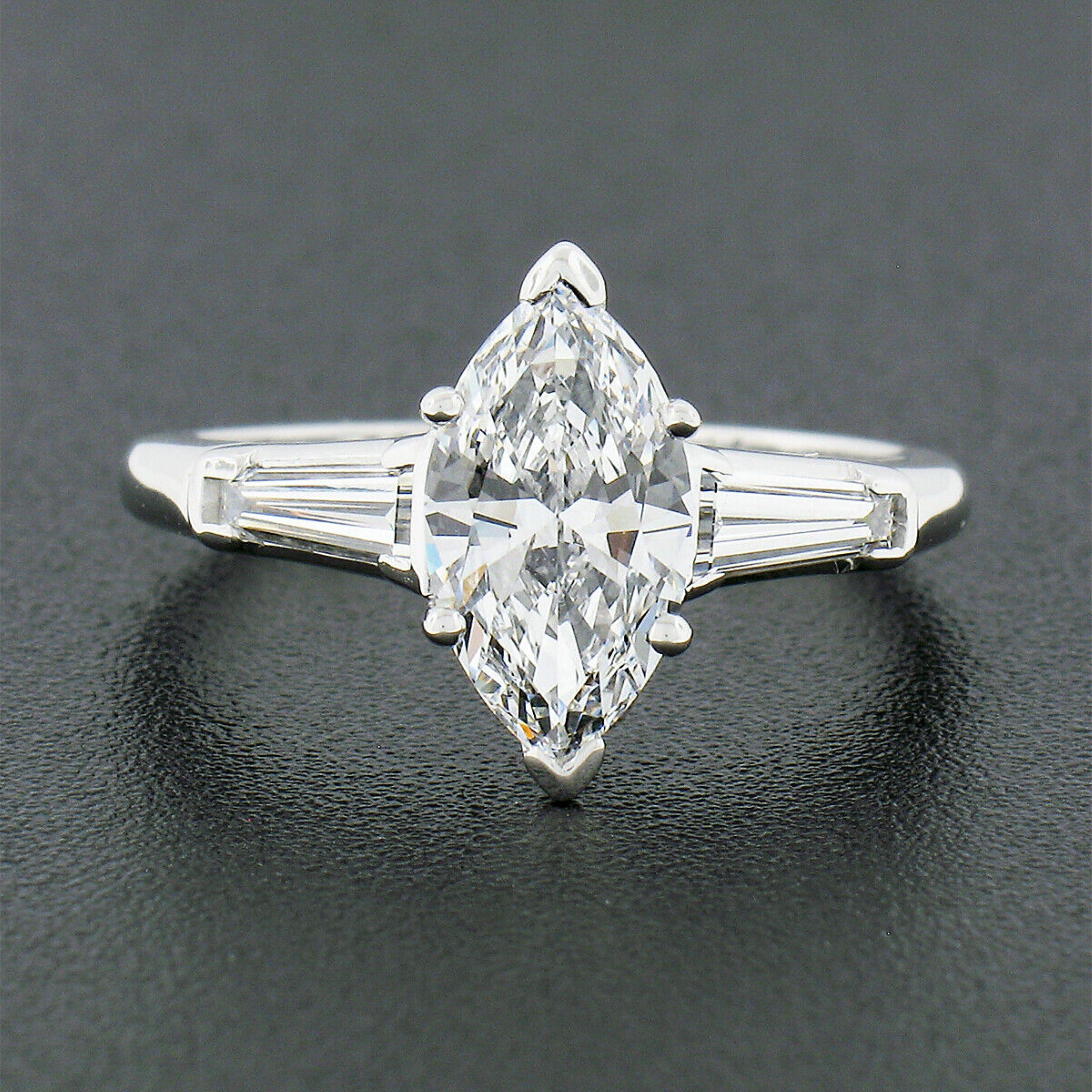 This classy mid-century engagement ring was crafted from solid 900 platinum. The ring features a gorgeous, GIA certified, marquise cut diamond solitaire prong set at its center. That center stone weighs exactly 1.10 carats and is absolutely TOP