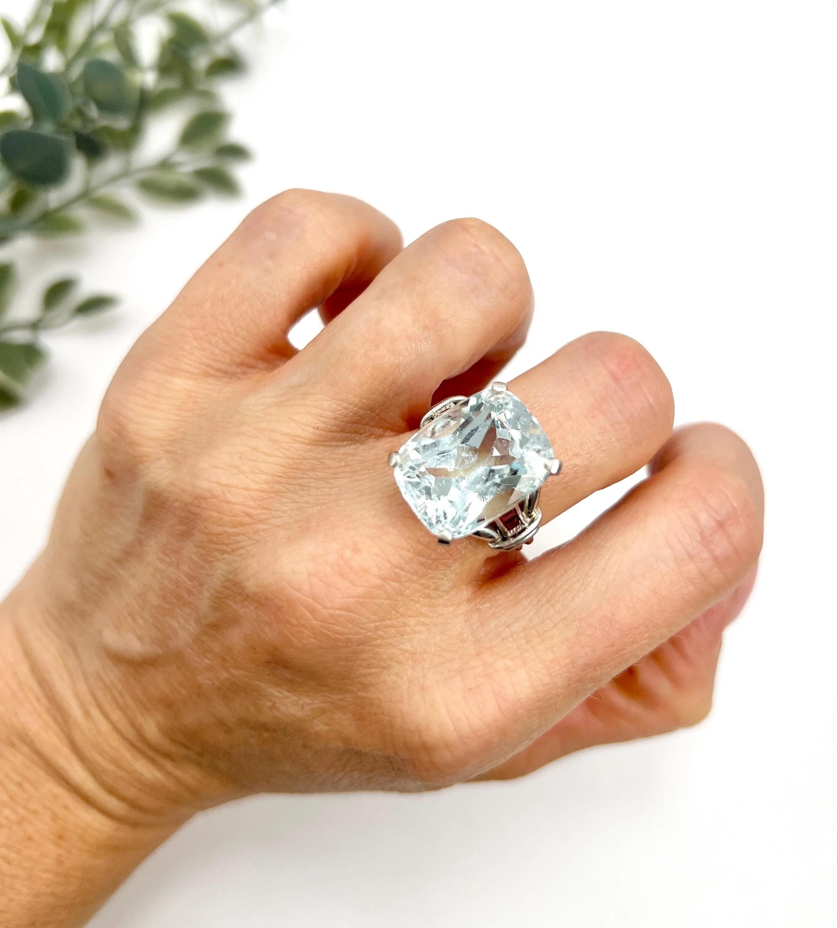 Vintage Aquamarine Cocktail Ring 

Platinum Tested

Circa 1960s

Step into a world of elegance with this fabulous vintage cocktail ring from the 1960s. At its heart lies a mesmerising cushion-cut aquamarine stone, weighing approximately 12 carats,