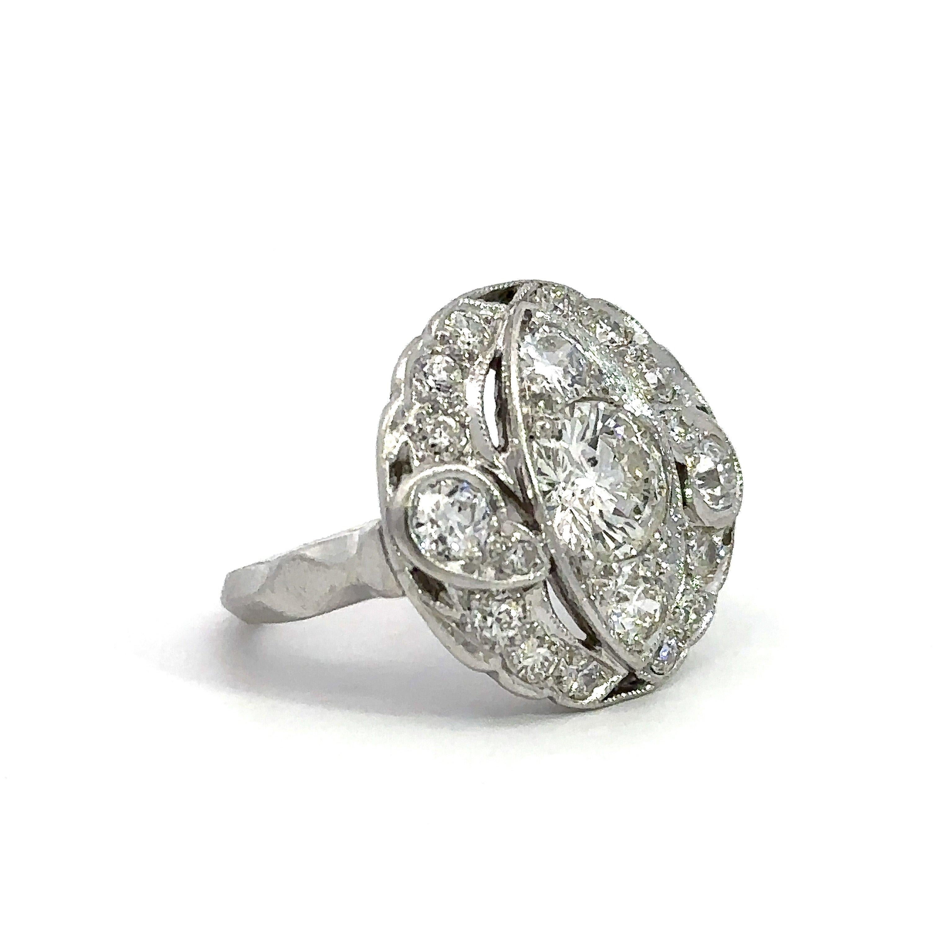 This vintage diamond cocktail ring, also called a dinner ring, dates from the late-1940's. It is crafted in platinum with one round 1.15CT center diamond with some warmth to the color (K Color) and imperfect clarity. The center diamond is surrounded