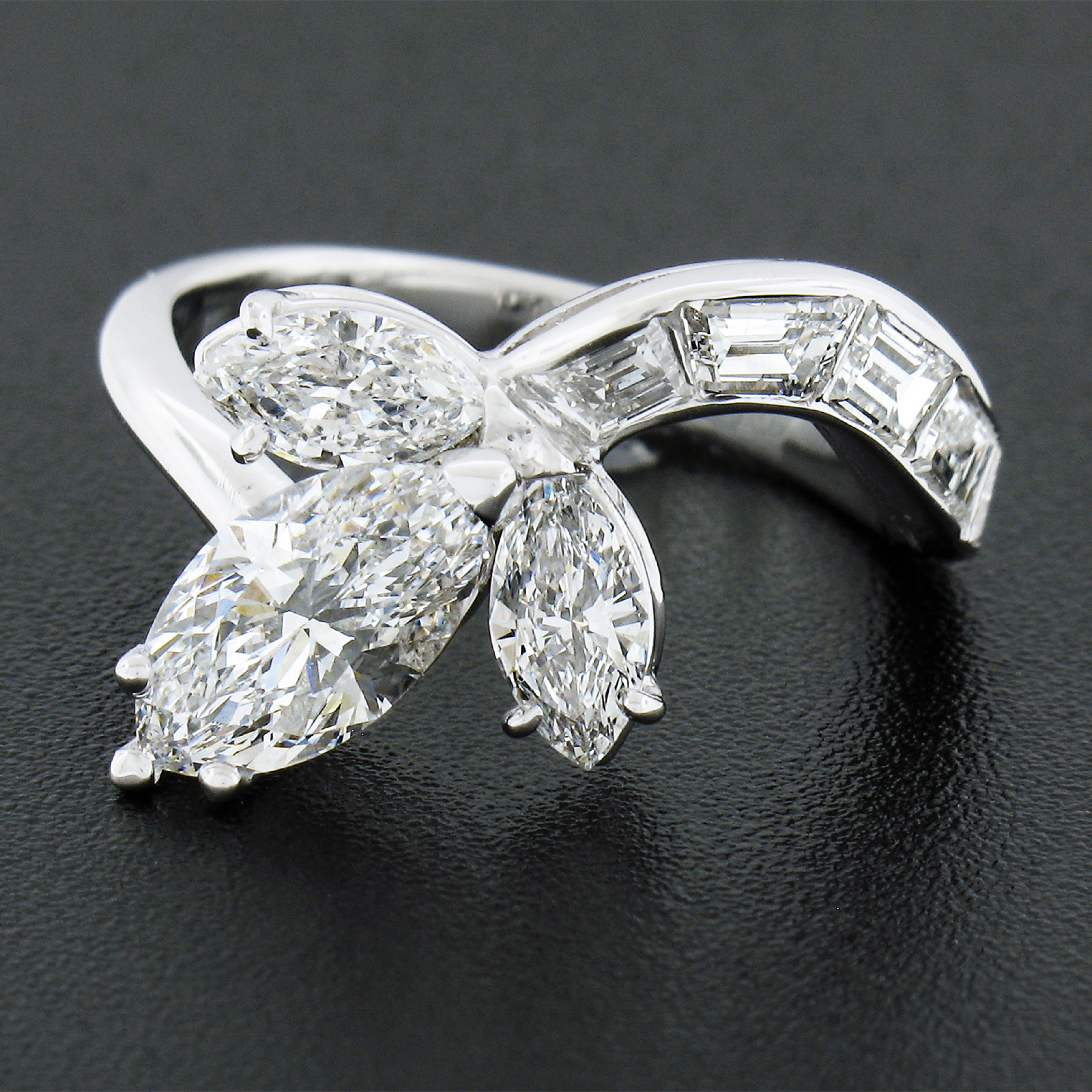 This incredibly chic and uniquely designed vintage diamond ring is crafted in solid platinum and features a breathtaking, GIA certified, marquise brilliant cut diamond neatly prong set on a slightly elevated open basket at the center of the design