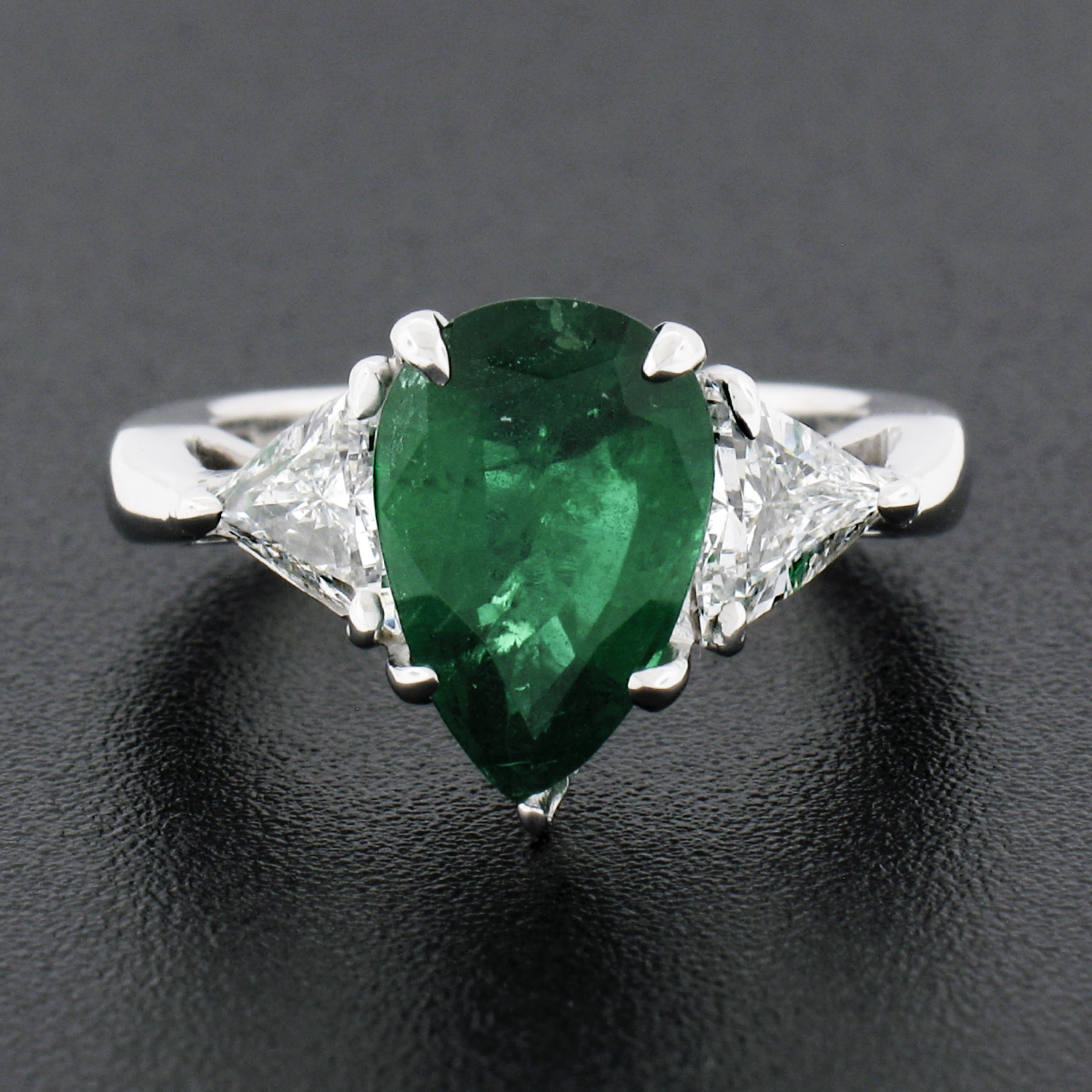Here we have a magnificent vintage emerald and diamond three-stone ring that is crafted in solid platinum. The ring features a gorgeous, GIA certified, natural emerald stone that displays a very rare and truly incredible vivid green color with