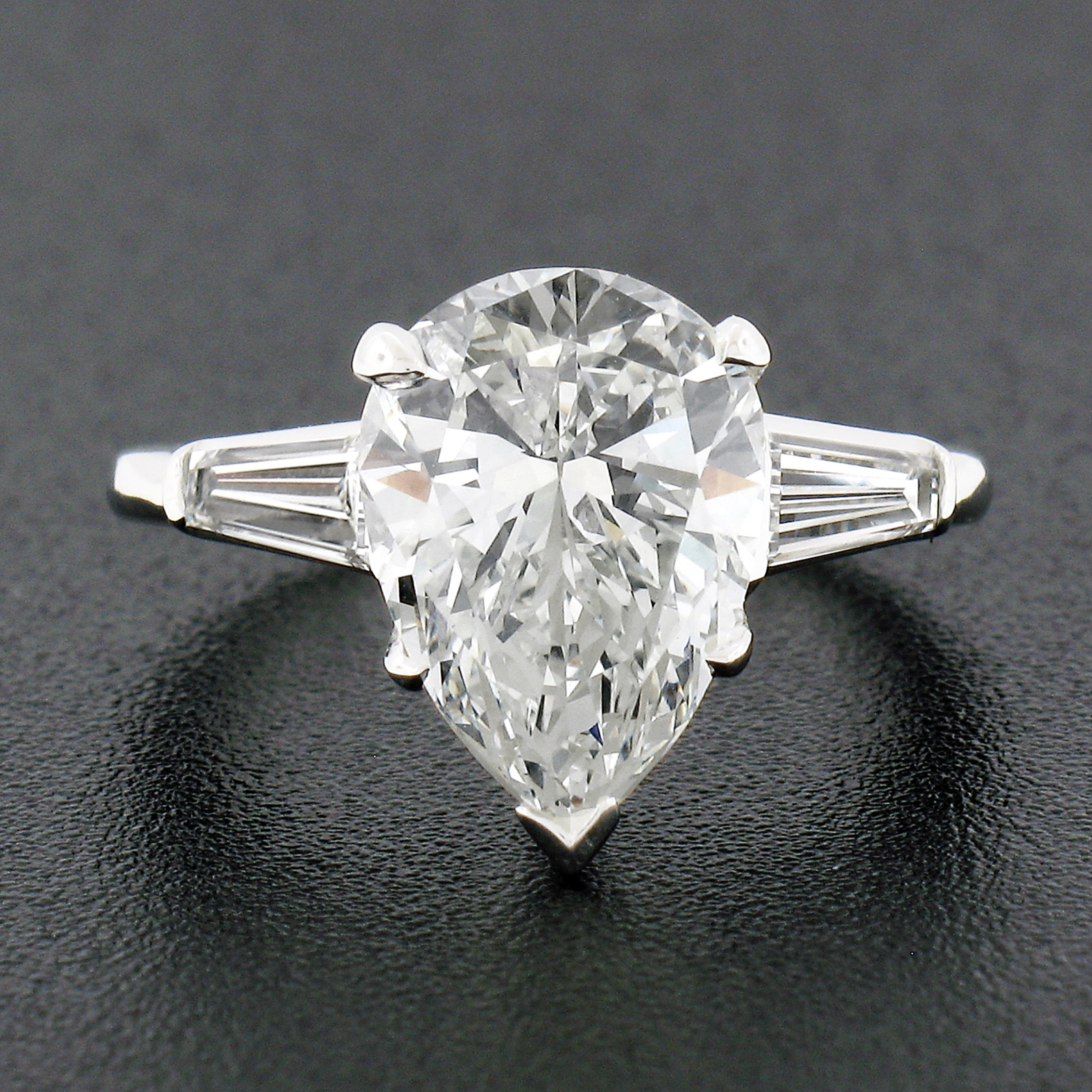 This dramatic diamond engagement ring is very well crafted in a solid platinum classic setting that carries a stunning, GIA certified, pear brilliant cut diamond at its center. This gorgeous diamond is certified by GIA as weighing 3.02 carats and