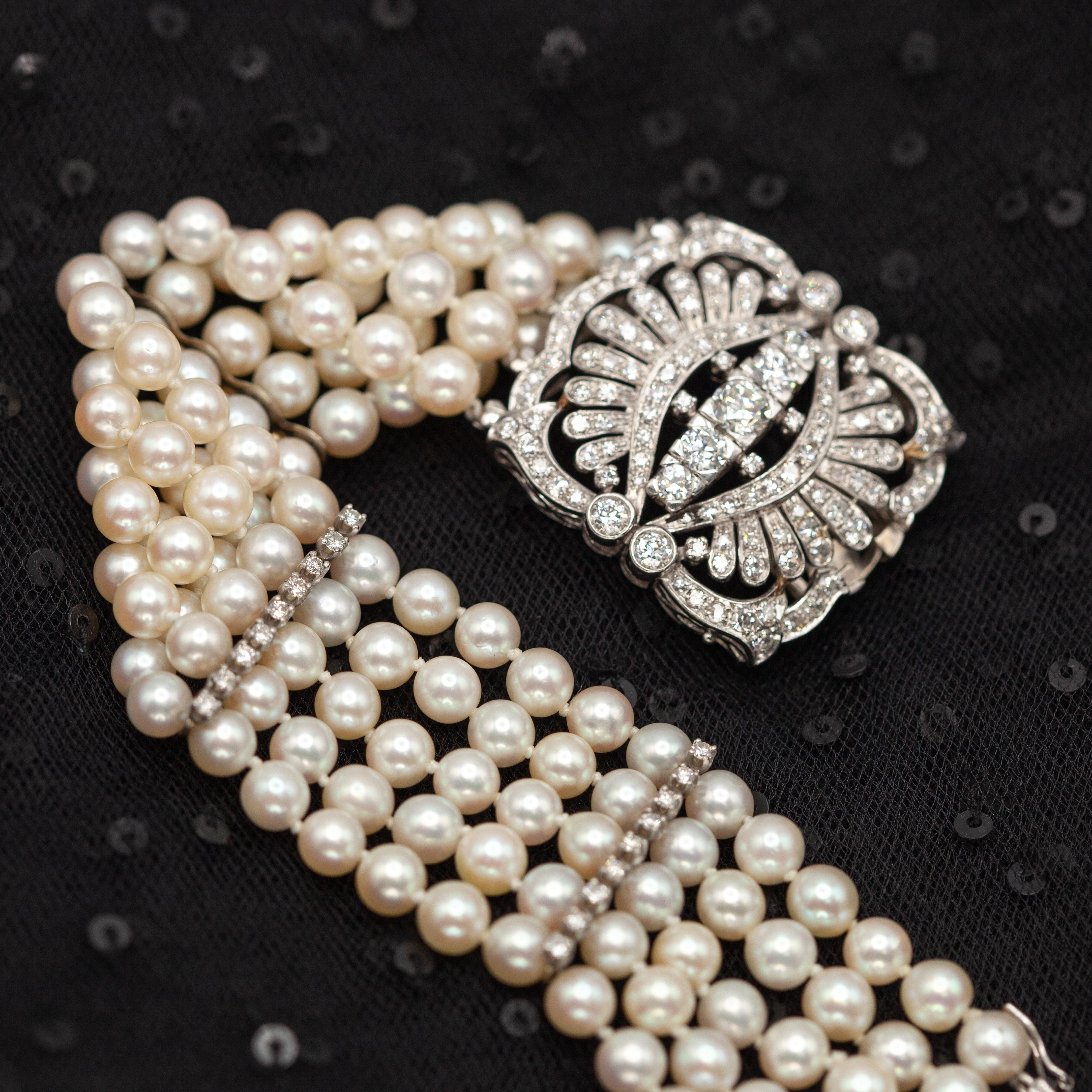Ein exquisites, mehrreihiges Perlenarmband mit fünf Reihen glänzender Zuchtperlen, die von einer atemberaubenden diamantbesetzten Schließe aus Platin gehalten werden. Der verschnörkelte Verschluss zeigt aufwändige durchbrochene und pavégefasste