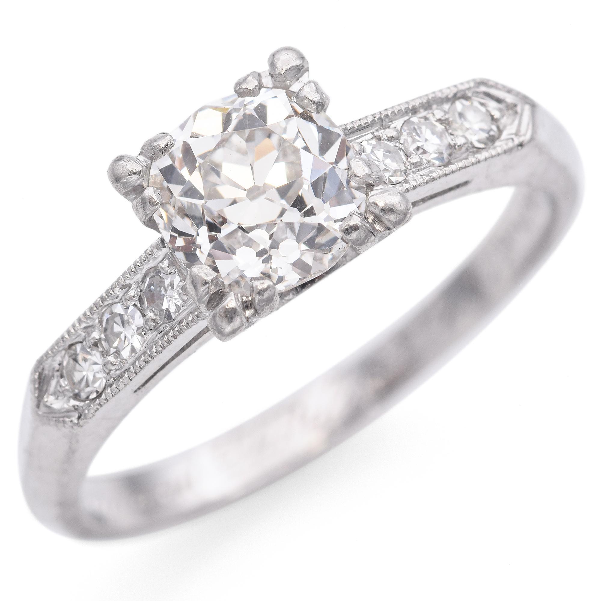 Dieser elegante Ring zeigt einen runden Diamanten in der Mitte, der in einer vierzackigen Fassung gefasst ist. Das Band ist mit einer Reihe kleinerer runder Diamanten geschmückt, die entlang der Schultern einen Hauch von Glanz verbreiten. Das Metall