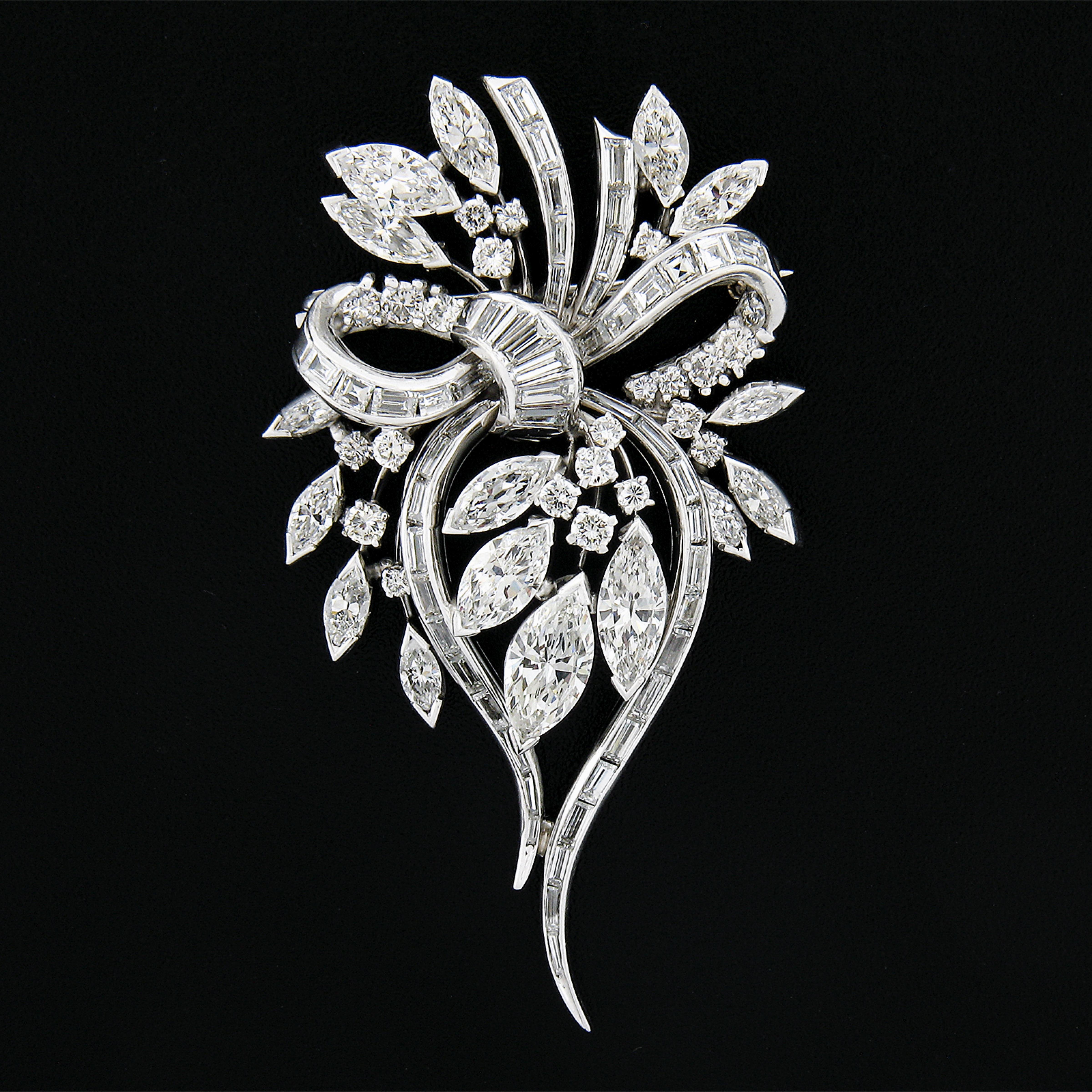 This truly magnificent and elegant mid-century diamond brooch is crafted in solid platinum and showcases a gorgeous floral design wrapped with an adorable knotted ribbon at its center. The flowers and leaves are done with old marquise and round