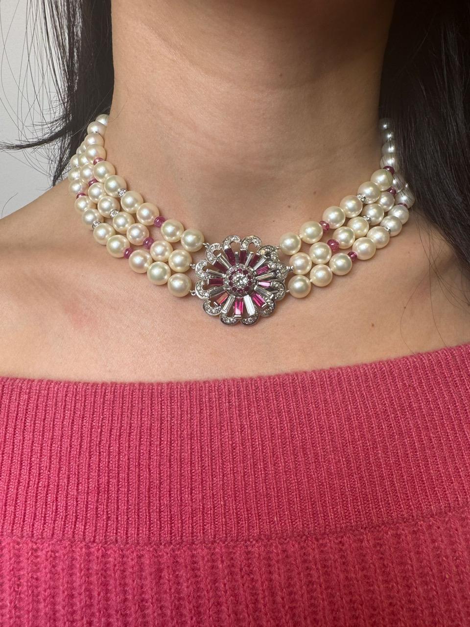 A graceful blend of classic elegance and retro glamour, this vintage necklace features three luxurious strands of luminous cultured pearls, accented by natural ruby beads totaling approximately 12.27 carats. Spaced intermittently with diamond