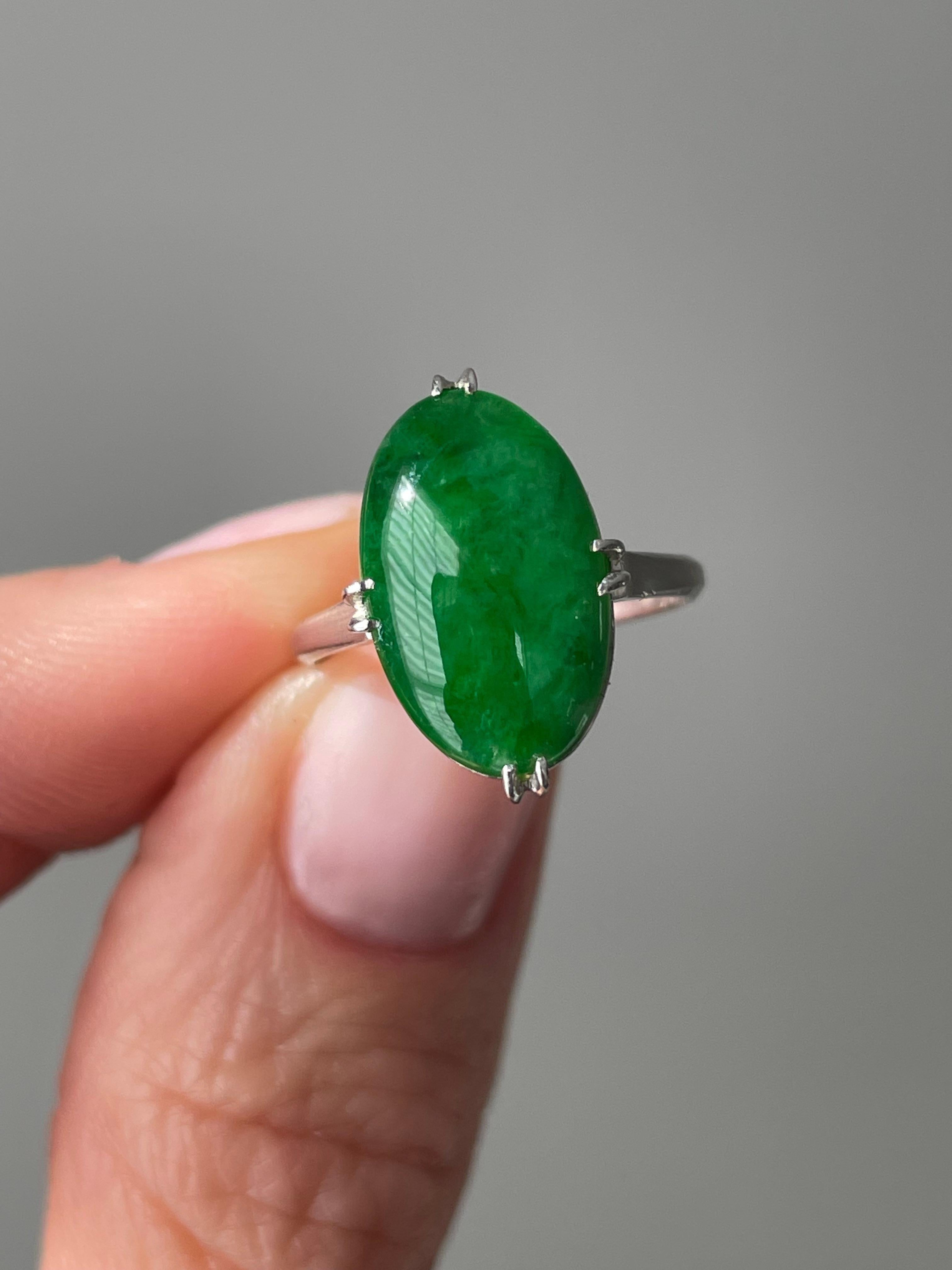 This classic Art Deco ring features a vibrant 4.26 carat natural jade cabochon presented in a hand fabricated platinum setting. The cabochon is framed by split prongs at the compass points and finished with an elegantly reticulated under gallery.