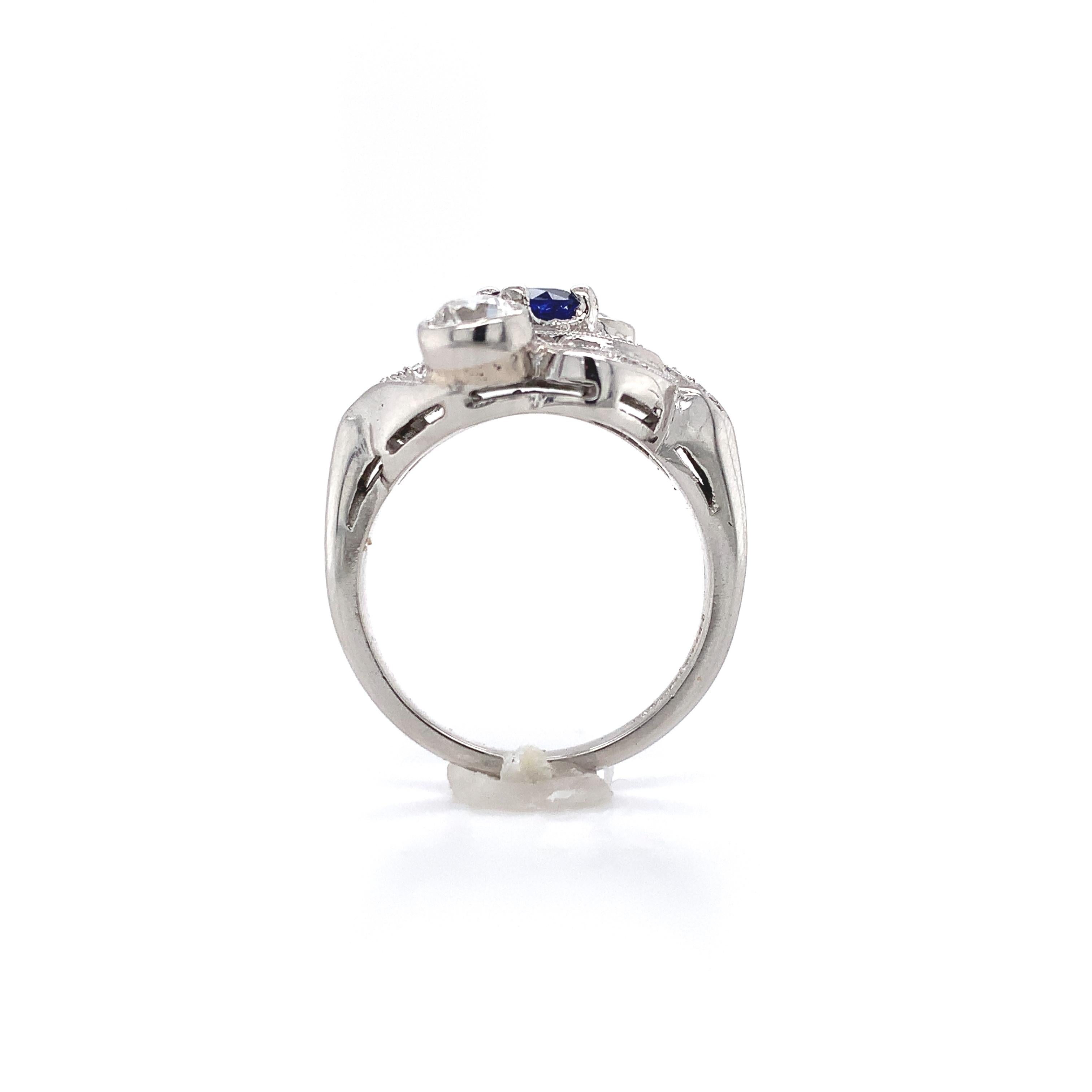 Antique platinum ring featuring a royal blue sapphire and 2 larger European cut diamonds. The sapphire weighs .54cts and measures about 4.8mm. The 2 European cut diamonds are bezel set and measure about 4.3mm. They weigh about .45ct each and have