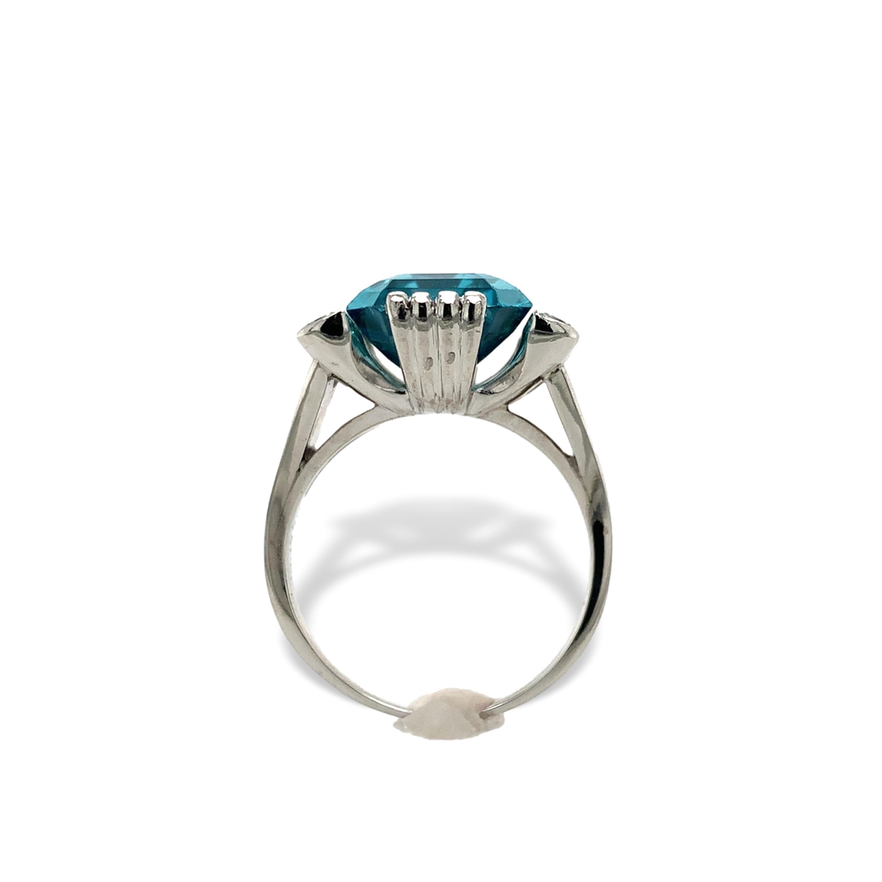 Platinum ring featuring an emerald cut blue zircon and 6 diamond accents. The blue zircon is a medium Caribbean blue color measuring about 13mm x 10.6mm x 6.5mm and weighing about 10 carats. There are 6 small round brilliant cut diamond accents