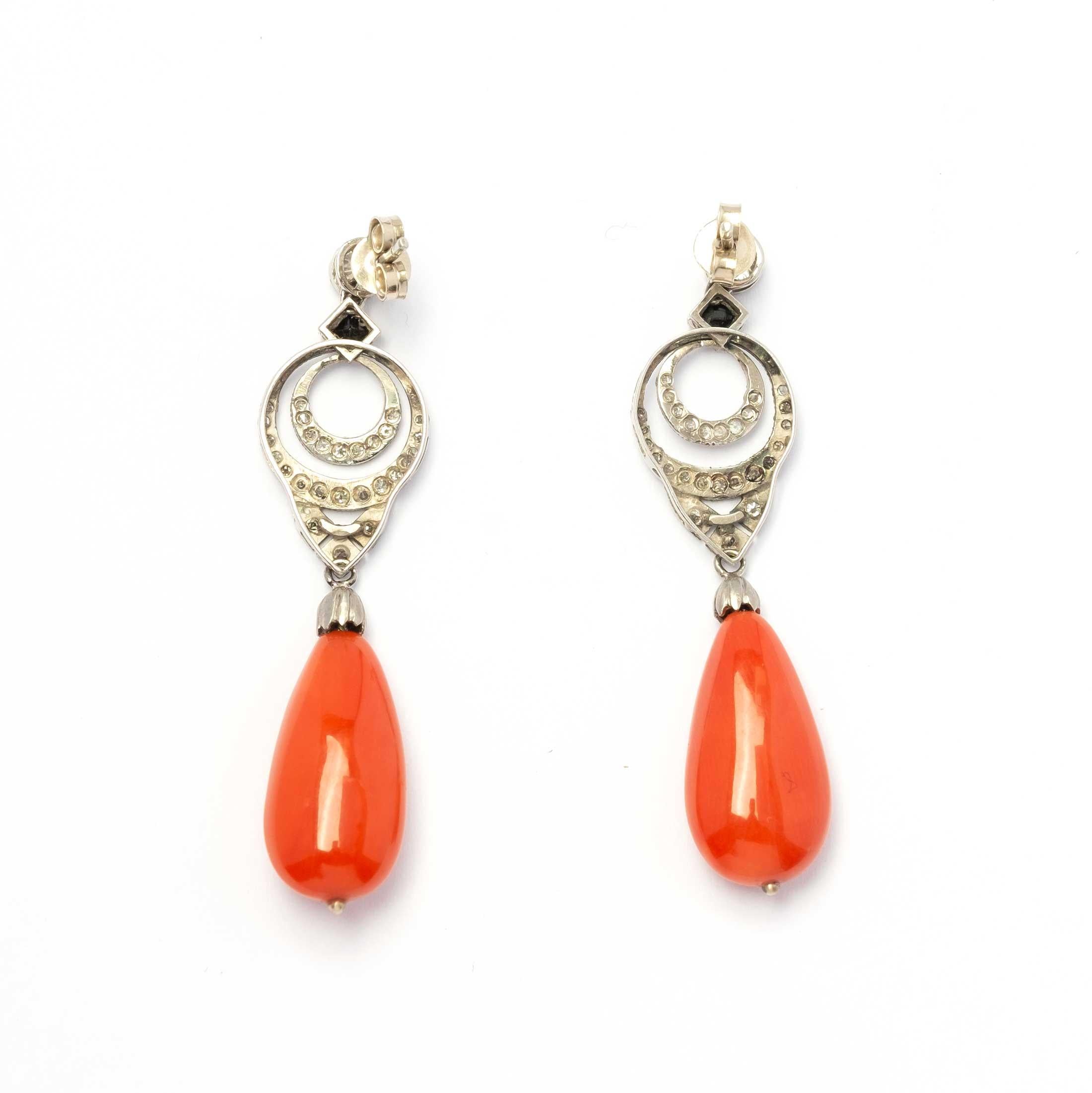Elegante Vintage-Ohrringe, gefasst in Platin mit Diamanten im Rundschliff (0,70 c.a.), kleinen Onyx-Highlights und zwei prächtigen natürlichen Korallentropfen.

Höhepunkte:
- Vintage-Ohrringe in Platin gefasst
- Naturdiamanten im Rundschliff für