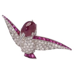 Broche vintage de platino con diamantes y rubíes en forma de colibrí.